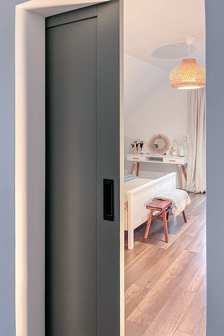eine offene Tür, die ein Fragment eines Schlafzimmers mit einem Bett und einem Schminktisch zeigt