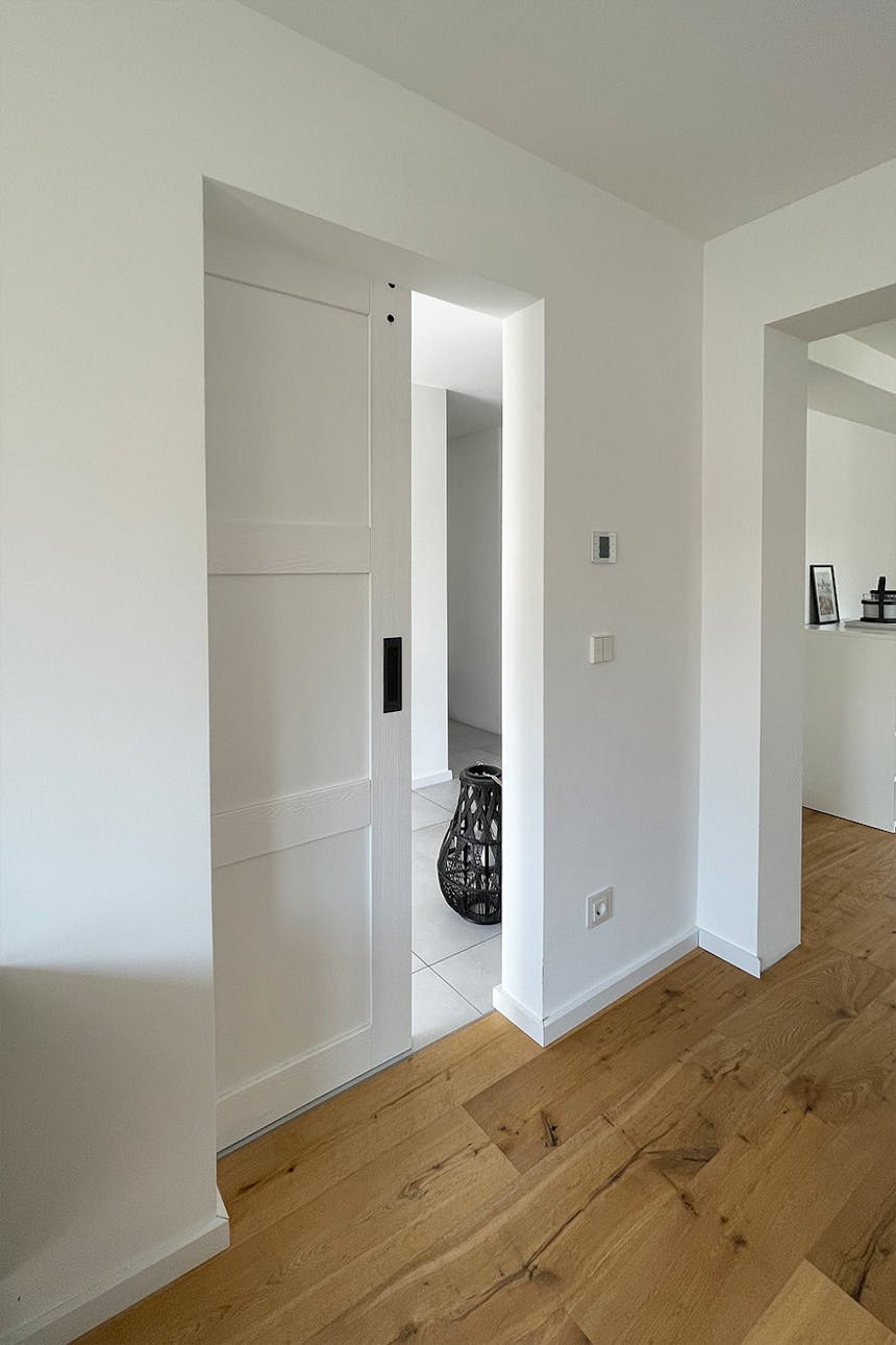 Moderne weiße Schiebetüren, weiße Holzschiebetüren, weiße Türen auf dem Hintergrund einer weißen Wand im Schlafzimmer