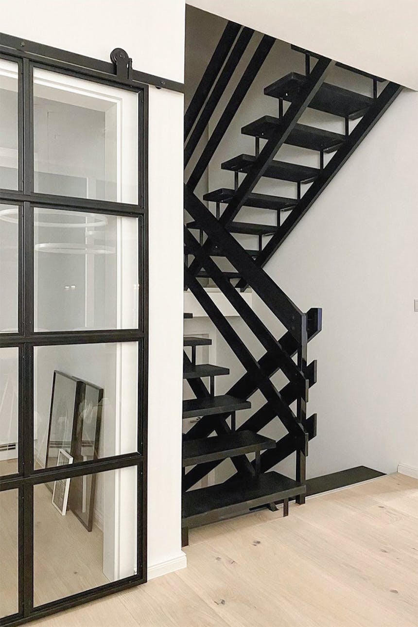 schwarze durchbrochene Treppe, Glastüren in einem schwarzen Metallrahmen