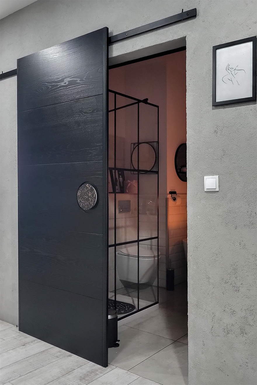 Offene schwarze Schiebetür, die einen Teil des Badezimmers zeigt