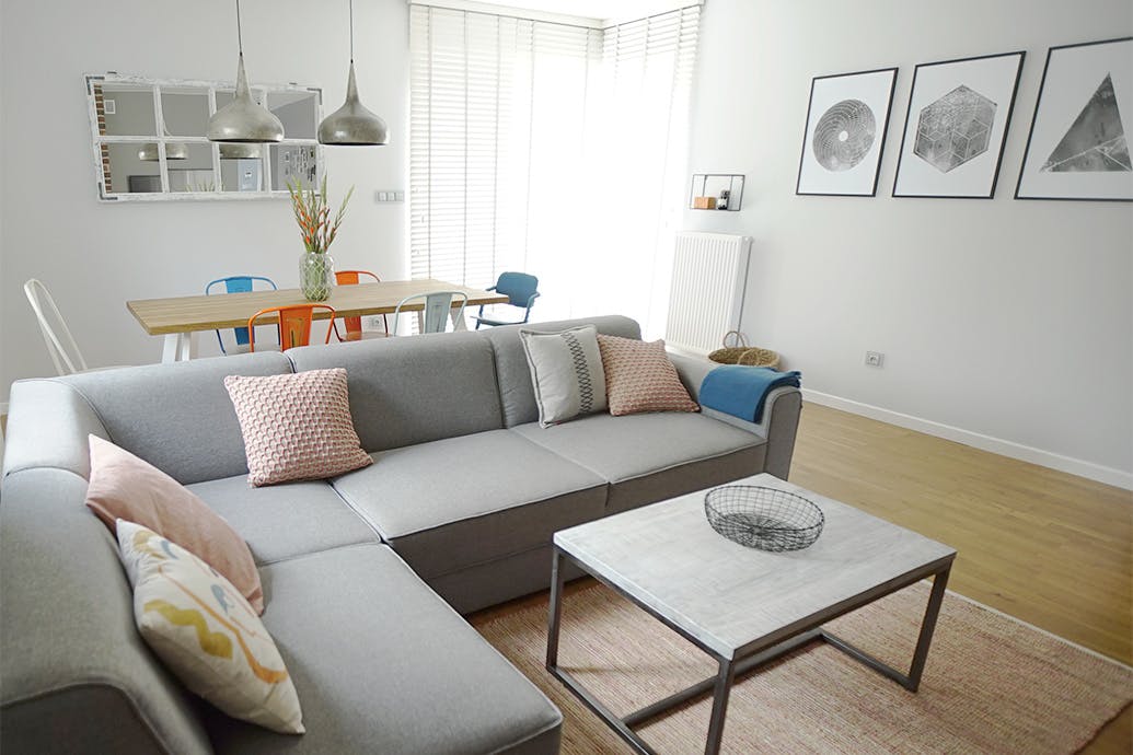 coussins décoratifs sur un canapé gris et une table basse carrée dans un agencement de salon