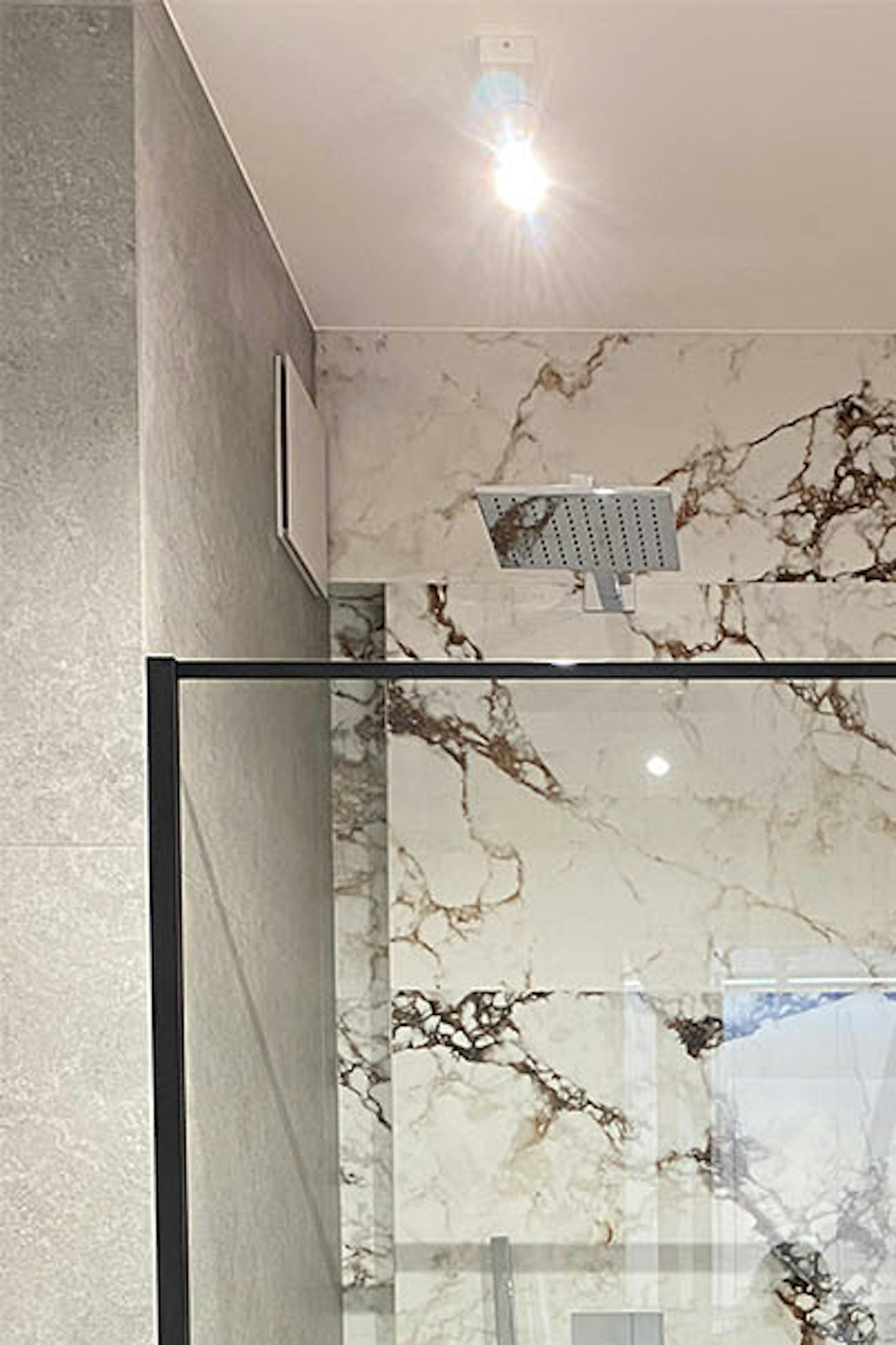cabines de douche minimalistes contre un mur décoré d'un motif en pierre dans une salle de bain moderne