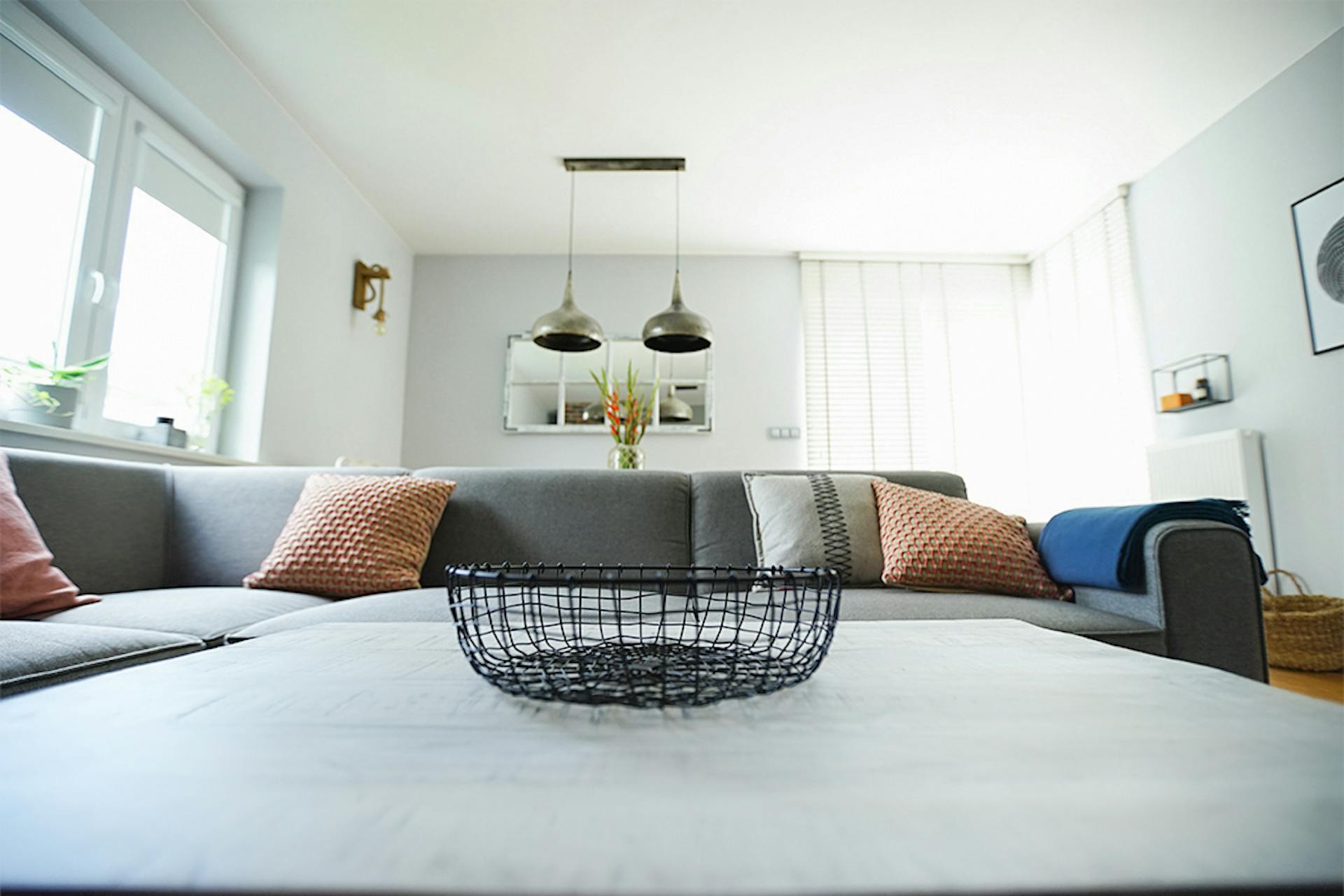 graues Sofa im Wohnzimmer, hängende Metall Lampen, bunte Kissen