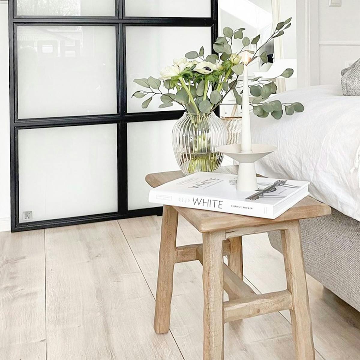 Holztisch neben dem Bett in einem Schlafzimmer im Nordic Stil