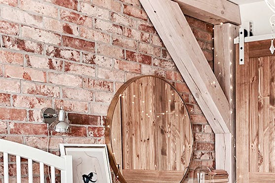 portes coulissantes en bois de style rustique sur un système coulissant blanc dans une chambre avec un mur de briques
