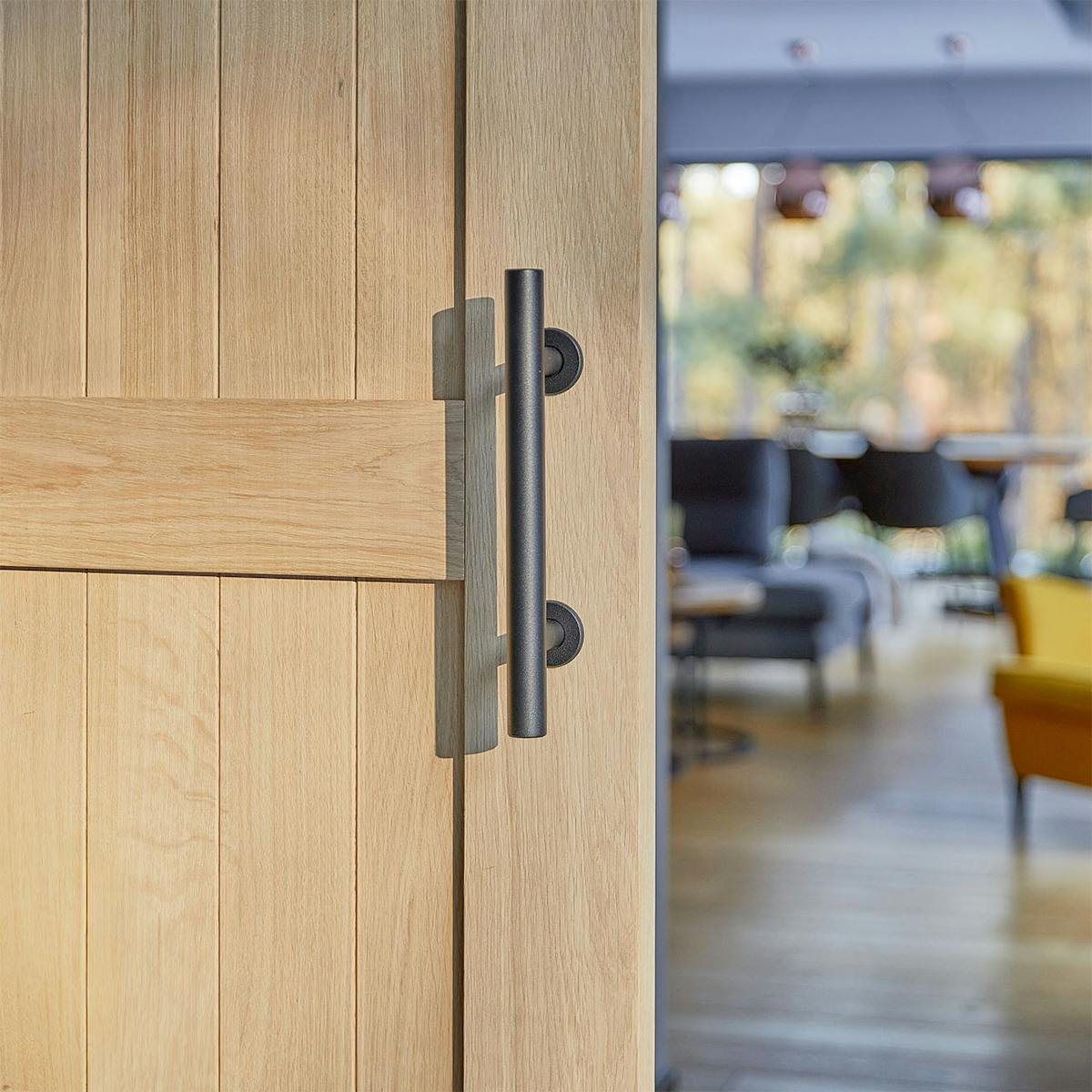 schwarzer Türgriff an einer Holztür aus natürlicher Eiche