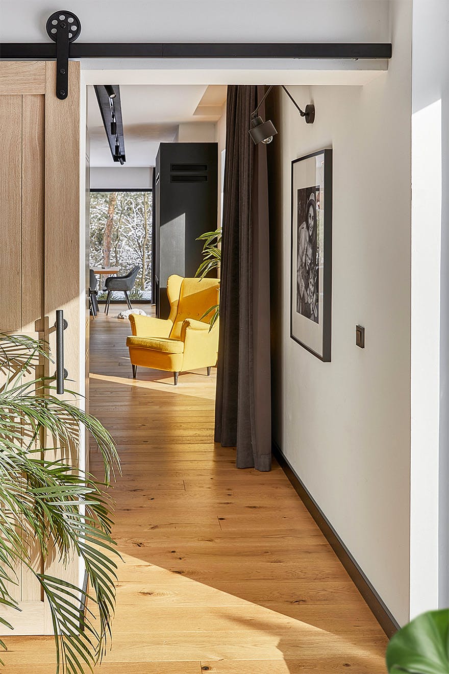 view of the hallway and part of the living room in a modern house with wooden floors and black accents
