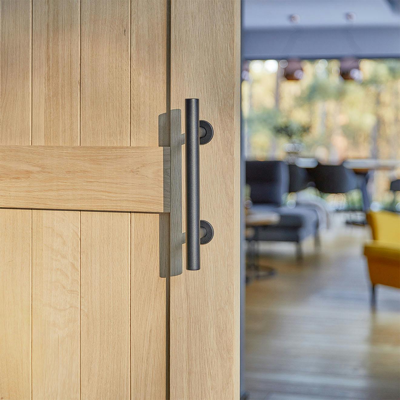 black door handle on a wooden door made of natural oak
