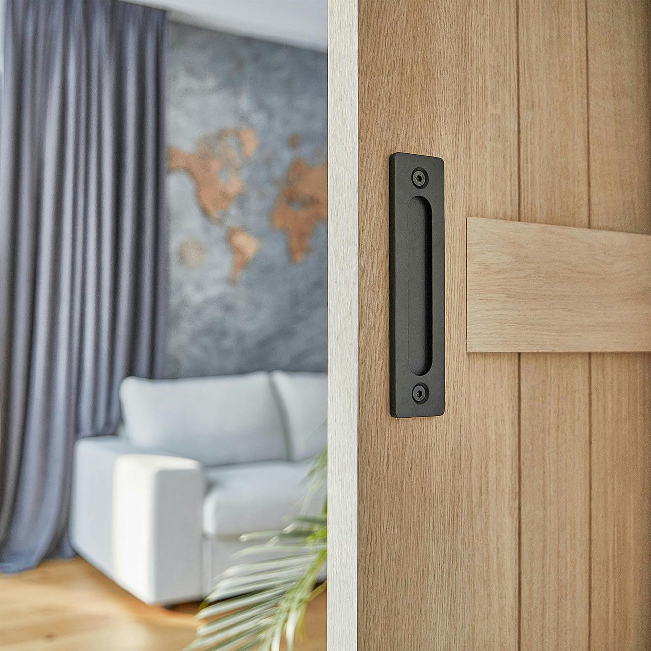 ajar wooden door revealing part of a room with a grey sofa and grey walls
