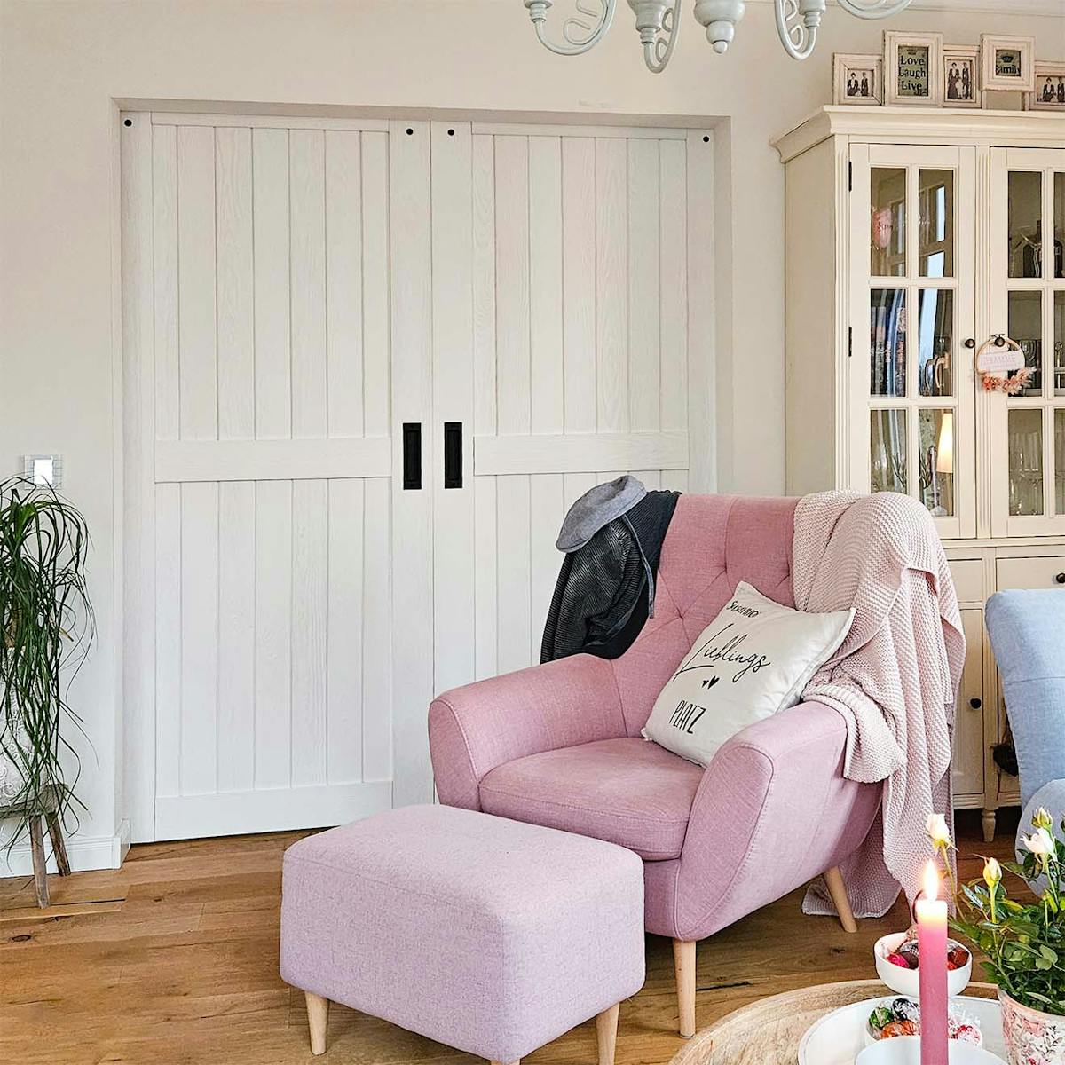 ein hellrosa Sessel neben einer geschlossenen weißen Schiebetür