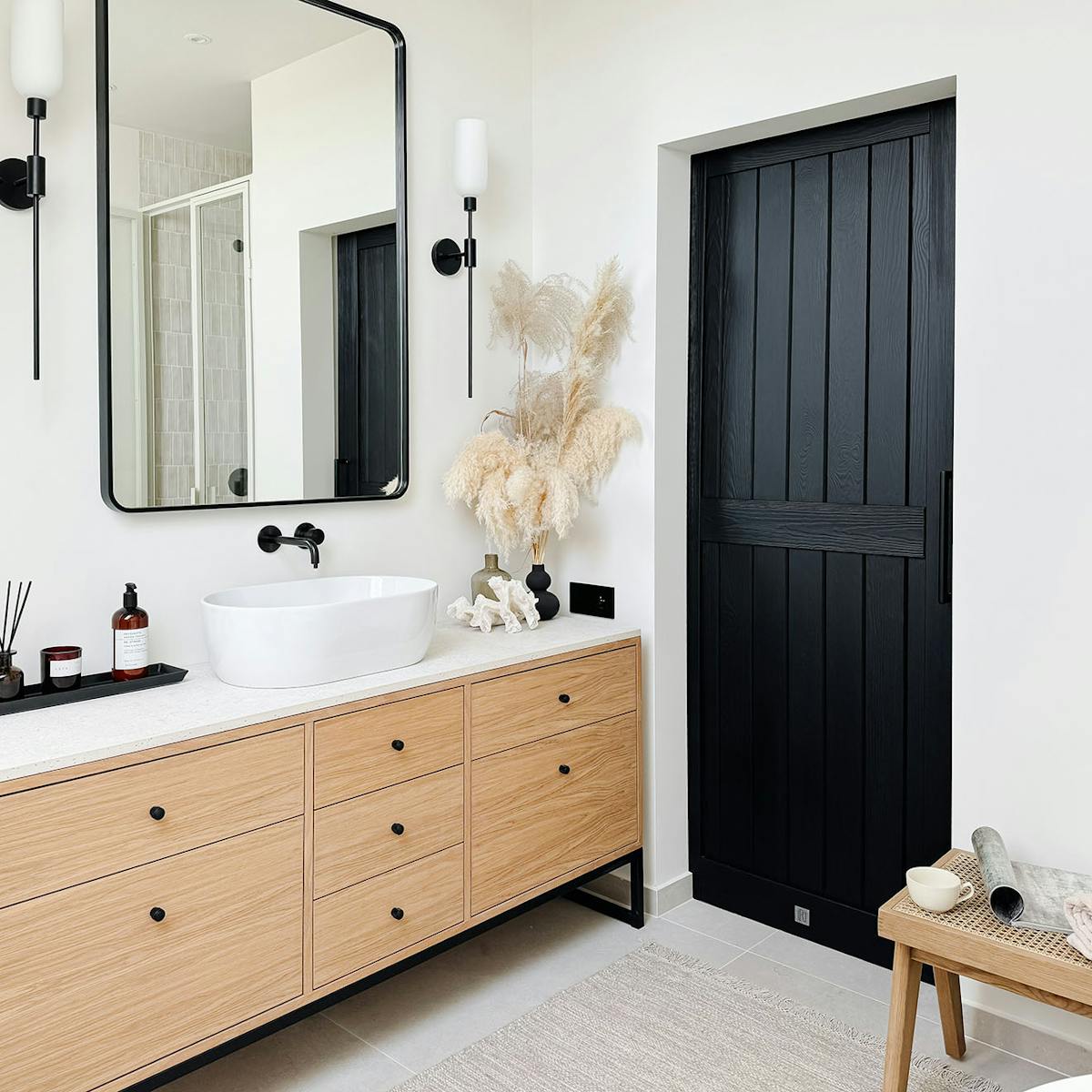Schwarze Schiebetüren neben einem Holzschrank mit weißem Waschbecken
