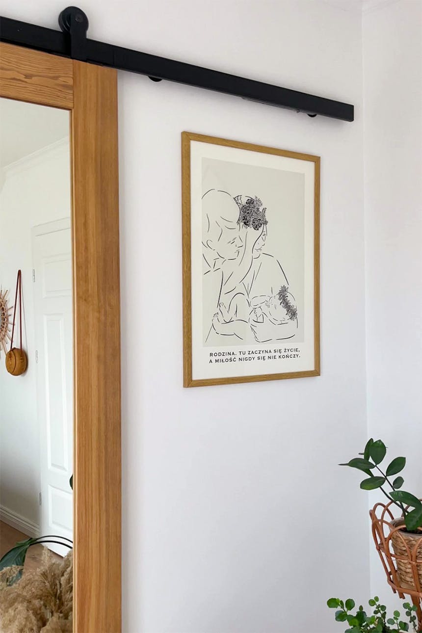 plakat w drewnianej ramie na ścianie obok drewnianych drzwi przesuwnych