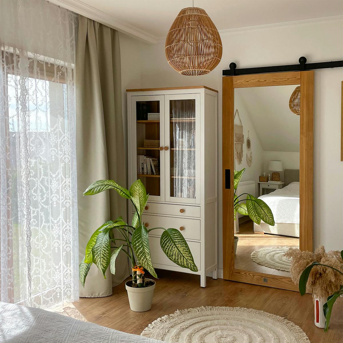 Schiebetür mit Spiegel neben einer weißen Vitrine mit Schubladen in einem Schlafzimmer mit Ankleidezimmer