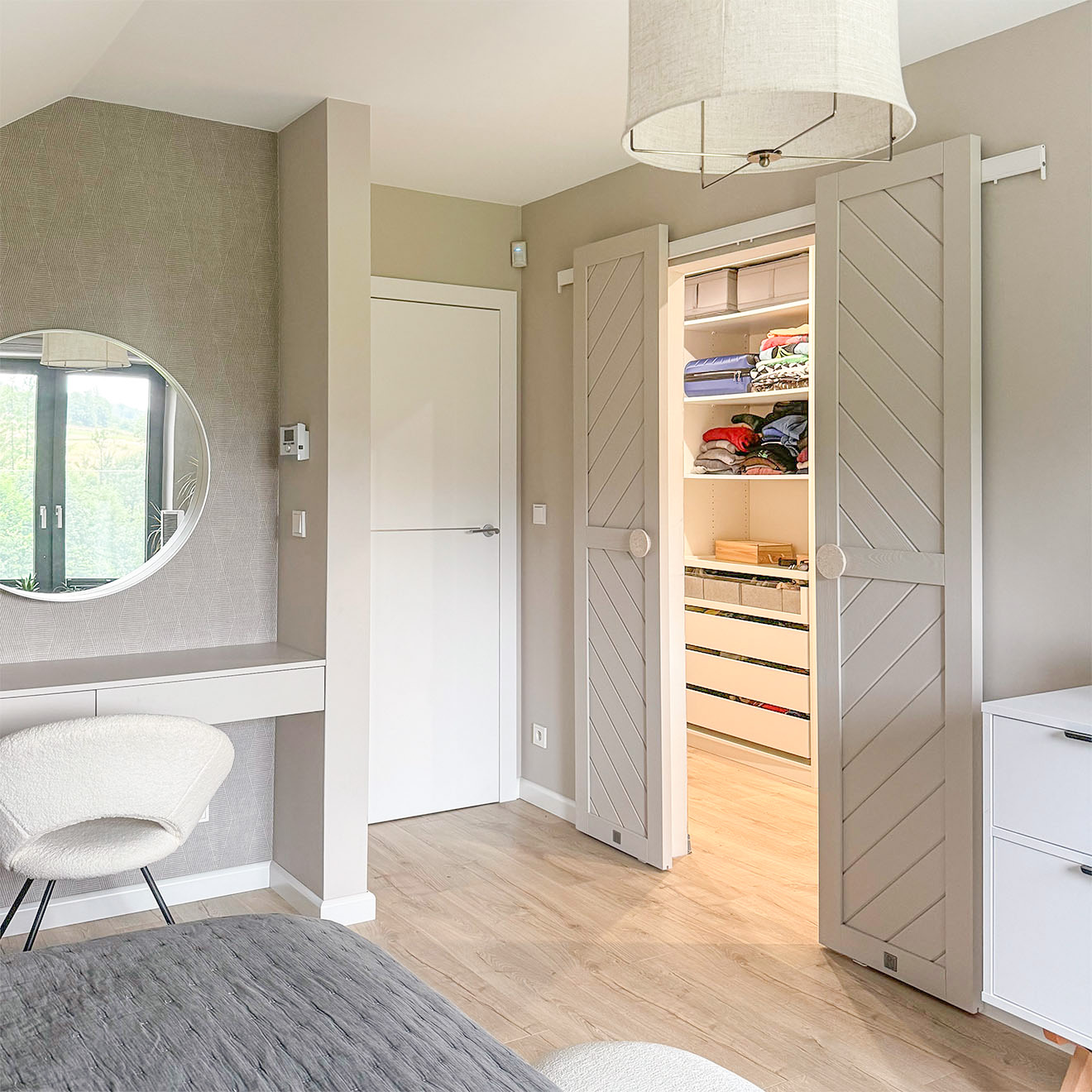 otwarte dwuskrzydłowe drzwi przesuwne ukazujące fragment garderoby w minimalistycznej sypialni