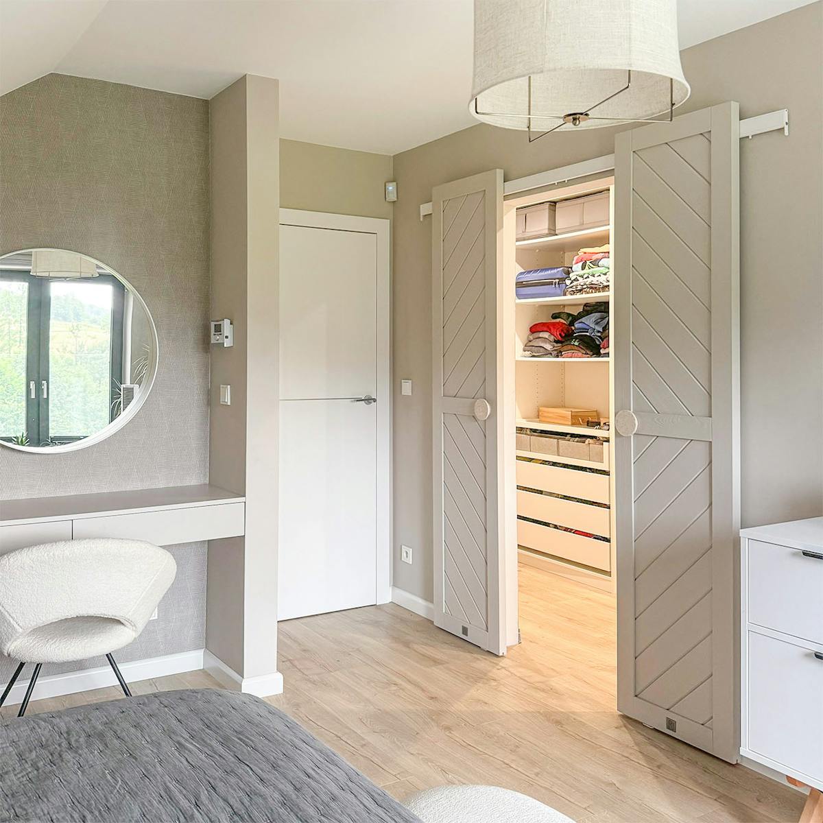 otwarte dwuskrzydłowe drzwi przesuwne ukazujące fragment garderoby w minimalistycznej sypialni