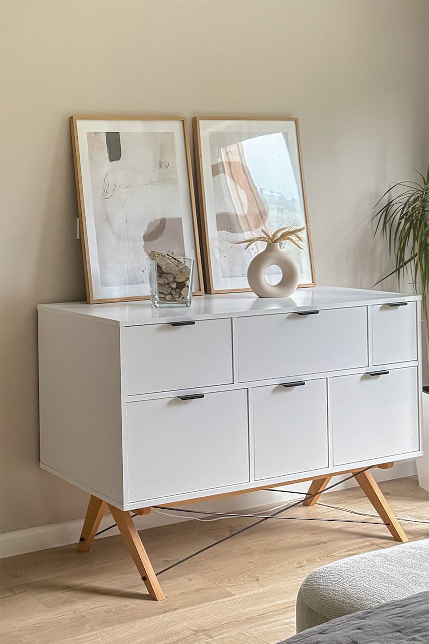 plakaty w ramkach na białej komodzie z głębokimi szufladami