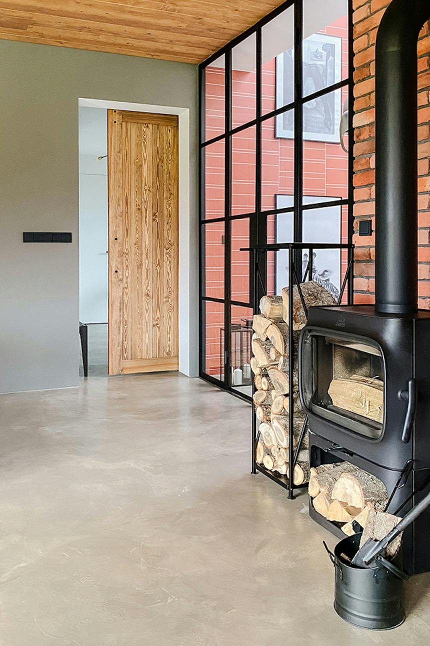 Spiegeltür im Vorraum, schwarzer Metall Kamin im Loft Stil, Glaswand, Mikrozement Boden