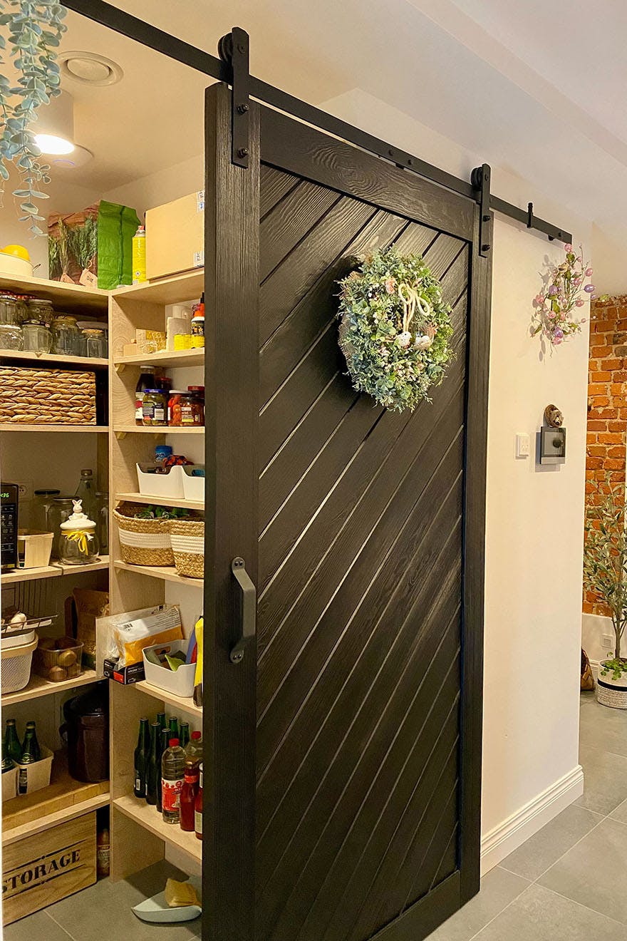 open pantry door, sliding door for the pantry, black sliding door made of solid wood, decorative wreath on the door