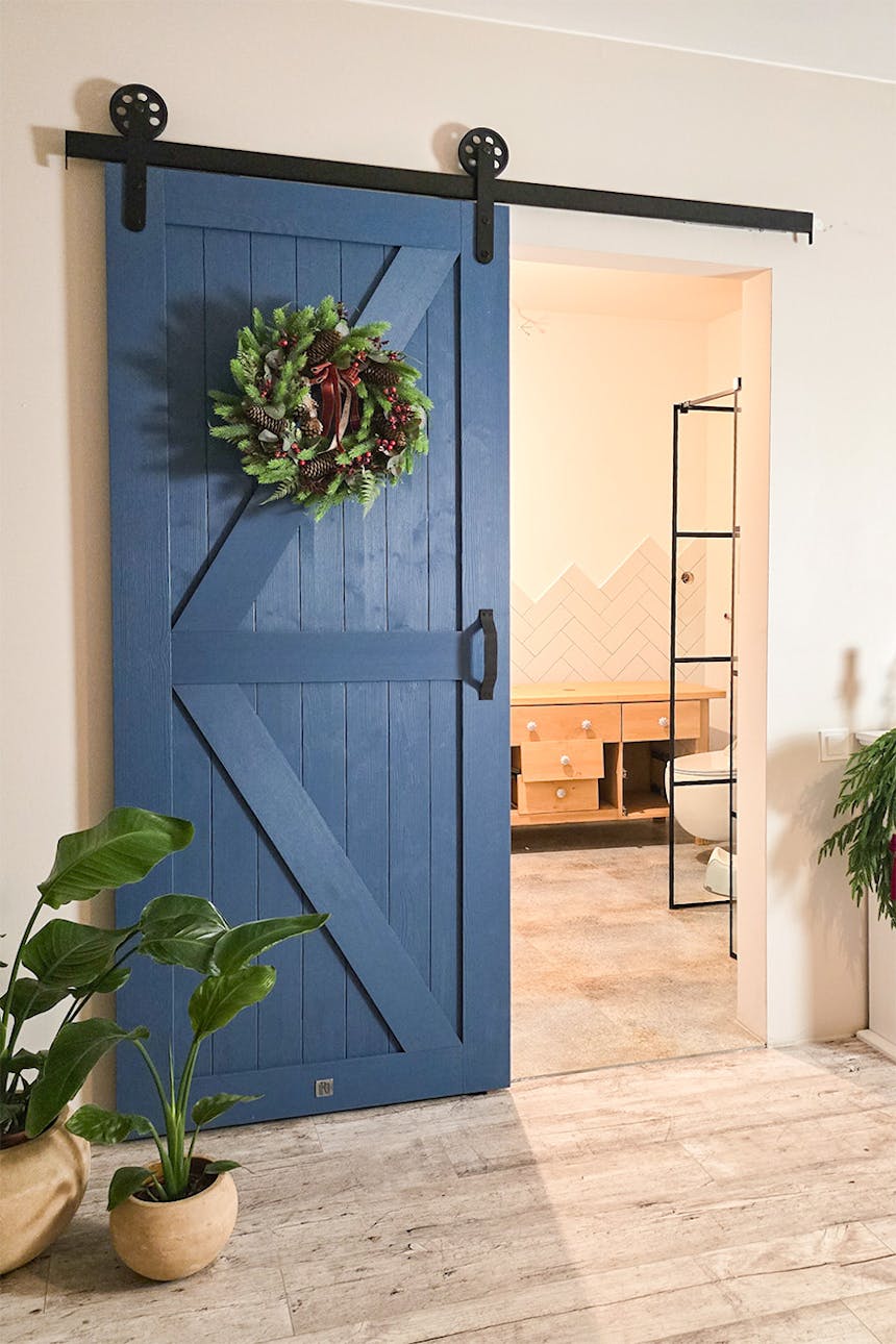 niebieskie drzwi drzwi przesuwne w stylu 'barn door" prowadzące do łazienki