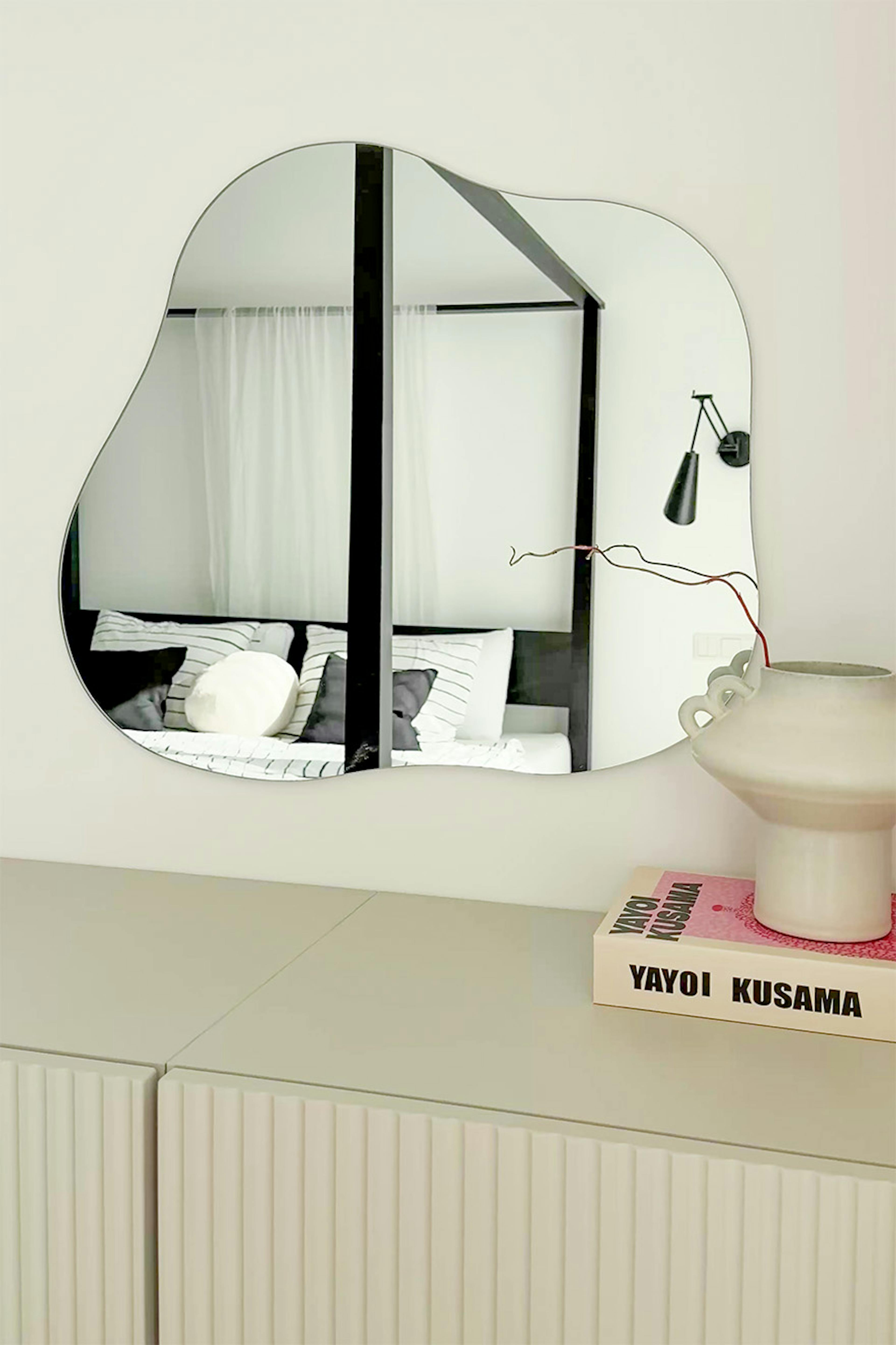un miroir mural moderne avec une forme irrégulière et organique dans un intérieur minimaliste