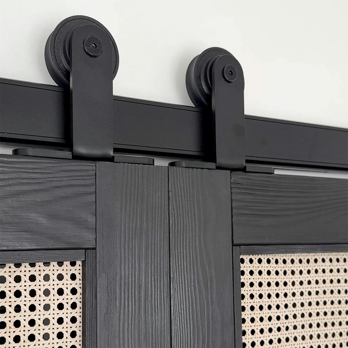 Nahaufnahme von schwarzen Schiebetüren mit Rattan-Paneelen und schwarzem Schiebesystem
