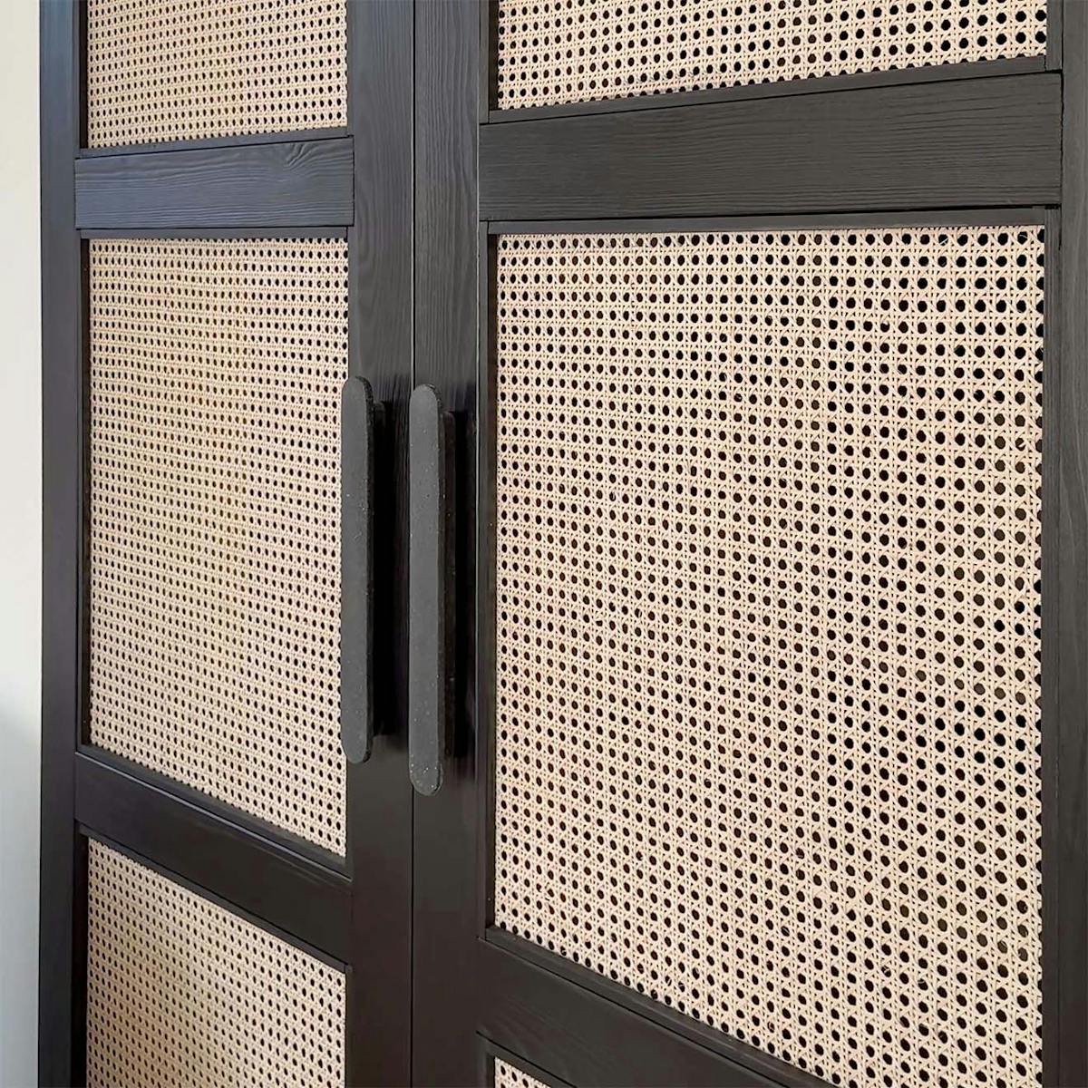 Nahaufnahme von schwarzen Holzschiebetüren mit geflochtenen Rattan-Paneelen und dunklen Griffen