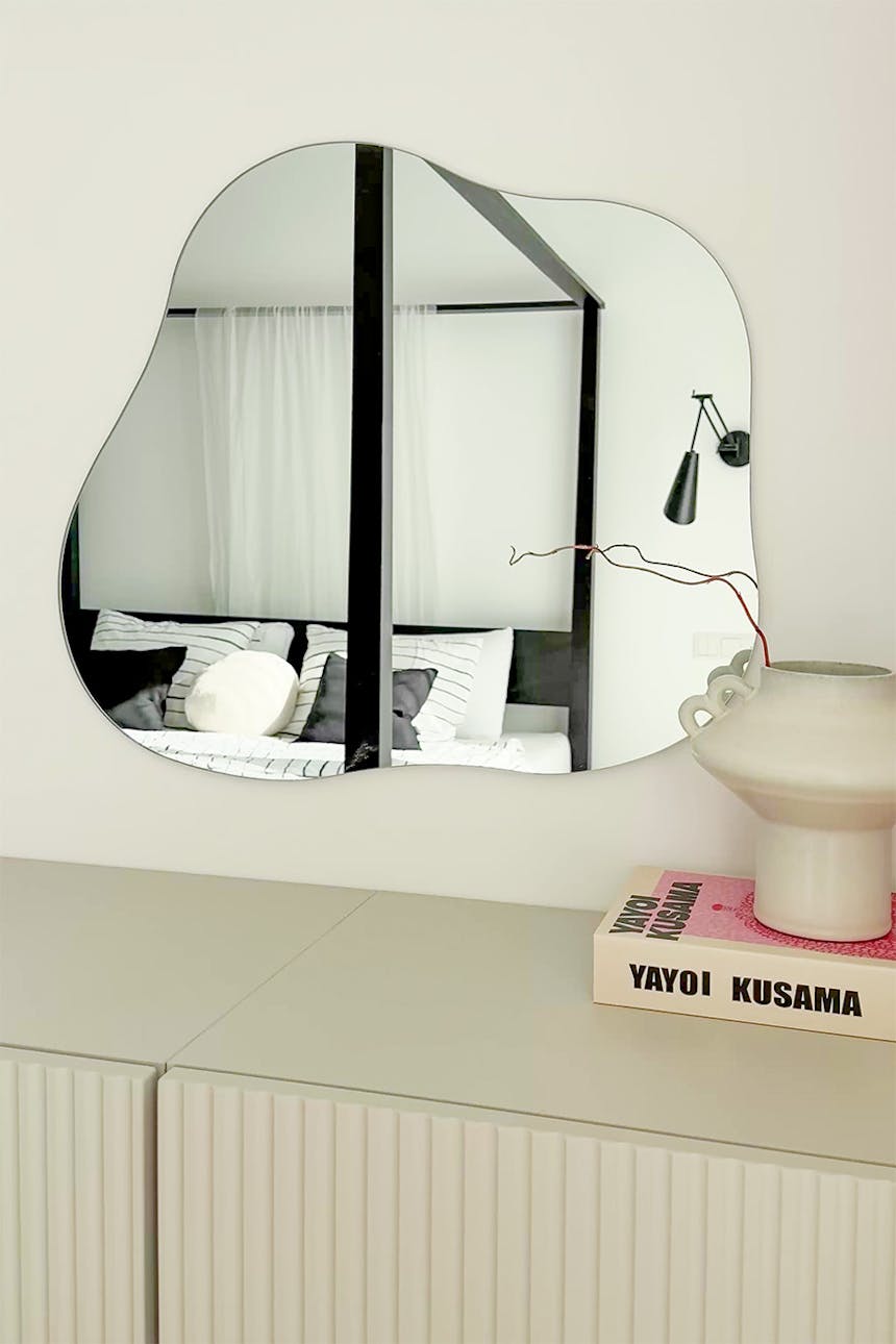 ein moderner Wandspiegel mit unregelmäßiger, organischer Form in einem minimalistischen Interieur