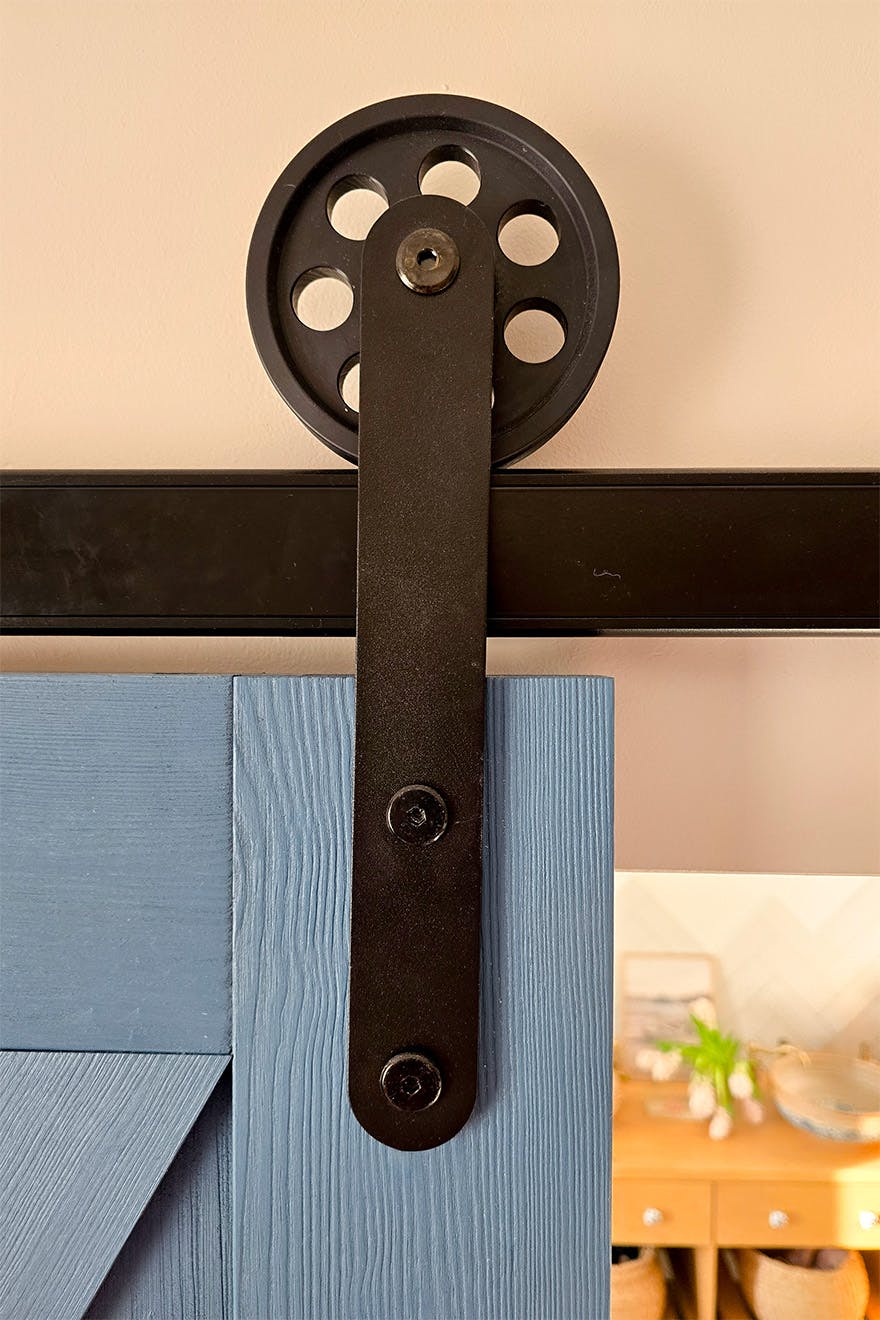 close-up of the black sliding system on a blue barn door (large sliding roller and track)