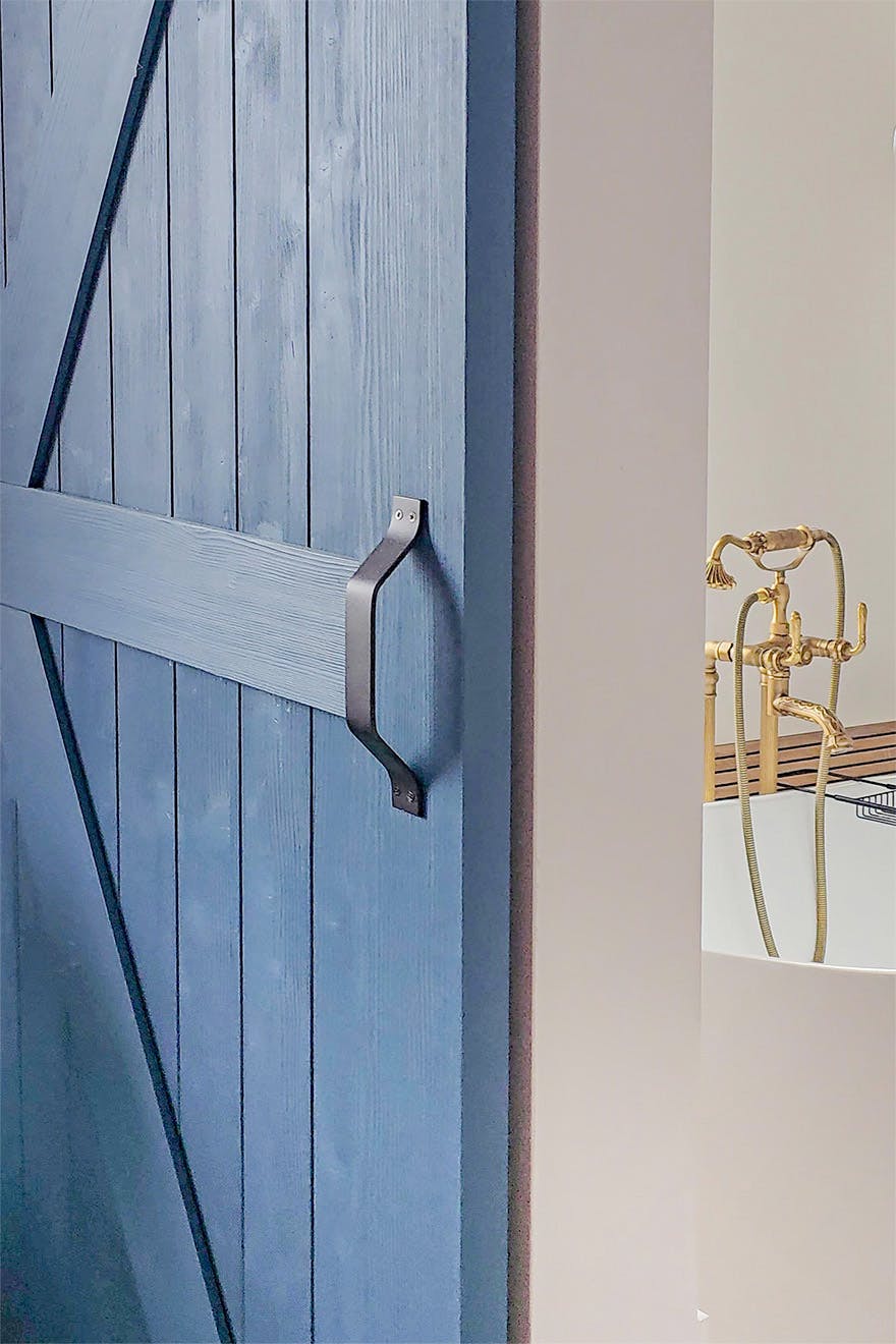 black handle of blue sliding door with view of retro bathroom fittings