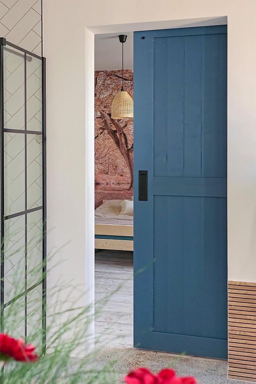 view from the bathroom through the open blue sliding door onto the photo wallpaper in the bedroom