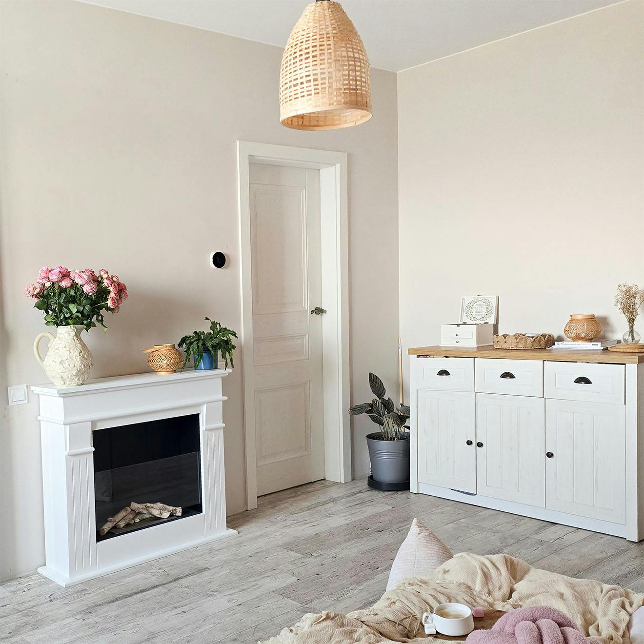 bedroom details: white wooden chest of drawers, fireplace, woven lamp, natural decorations on the fireplace and chest of drawers