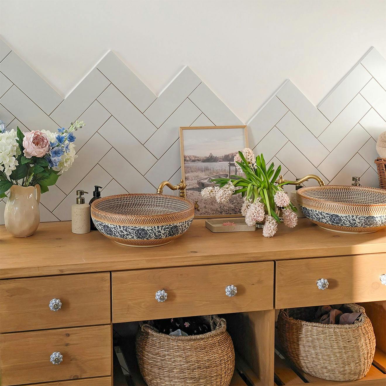 round ceramic countertop washbasins with ornate patterns and retro brass fittings against a herringbone tiled wall