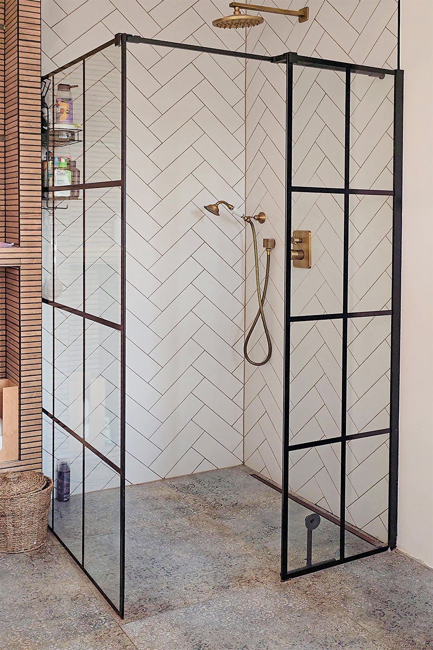 modern shower cubicle with black, industrial frames with retro fittings and wall tiles arranged in a herringbone pattern