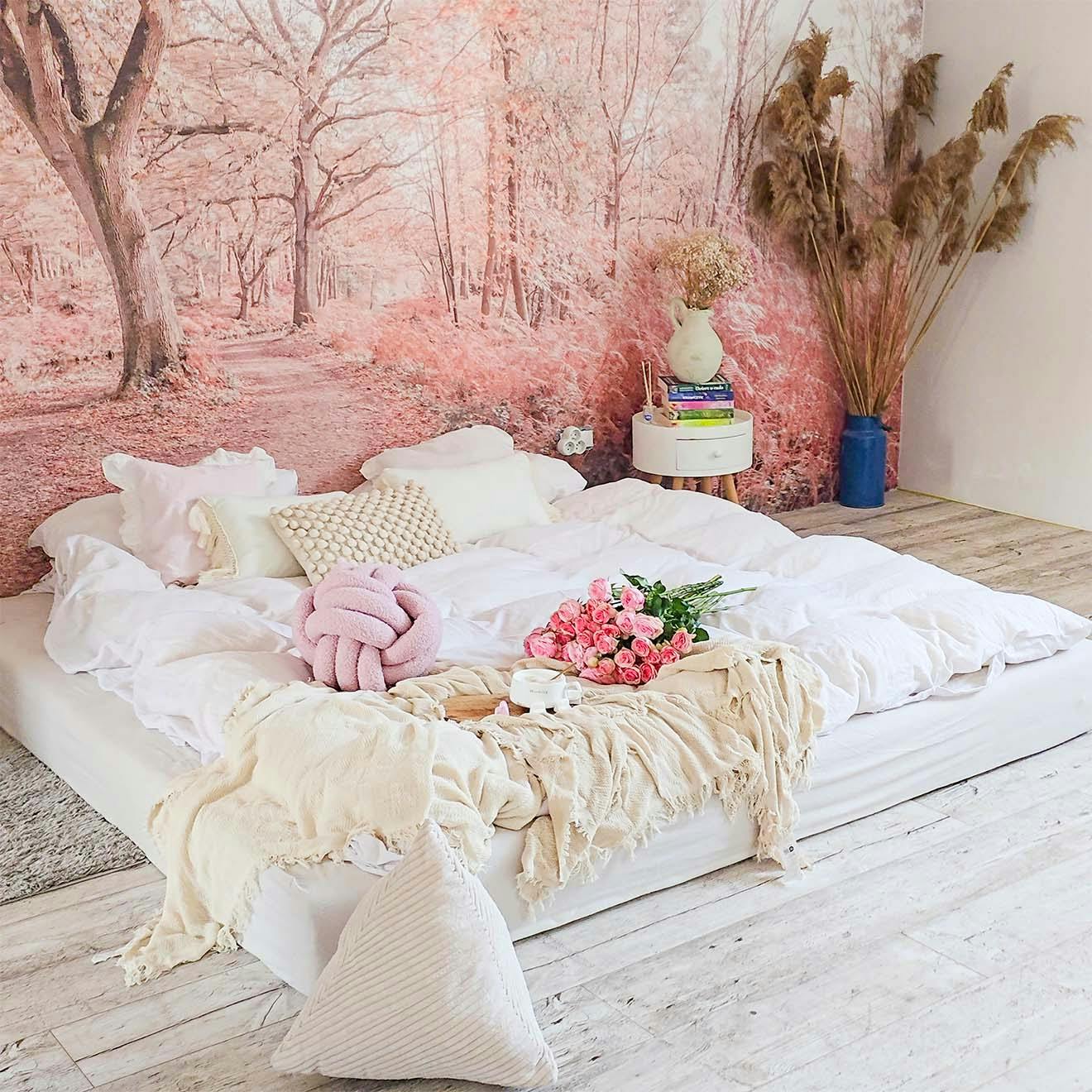 bedroom arrangement with a low bed, decorative pillows and an attractive photo wallpaper with a tree motif