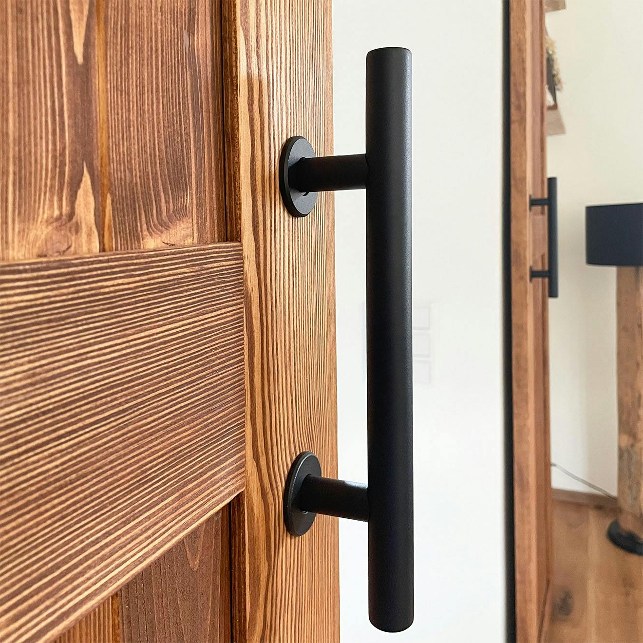 Detail of the black metal handle on a rustic wooden sliding door.