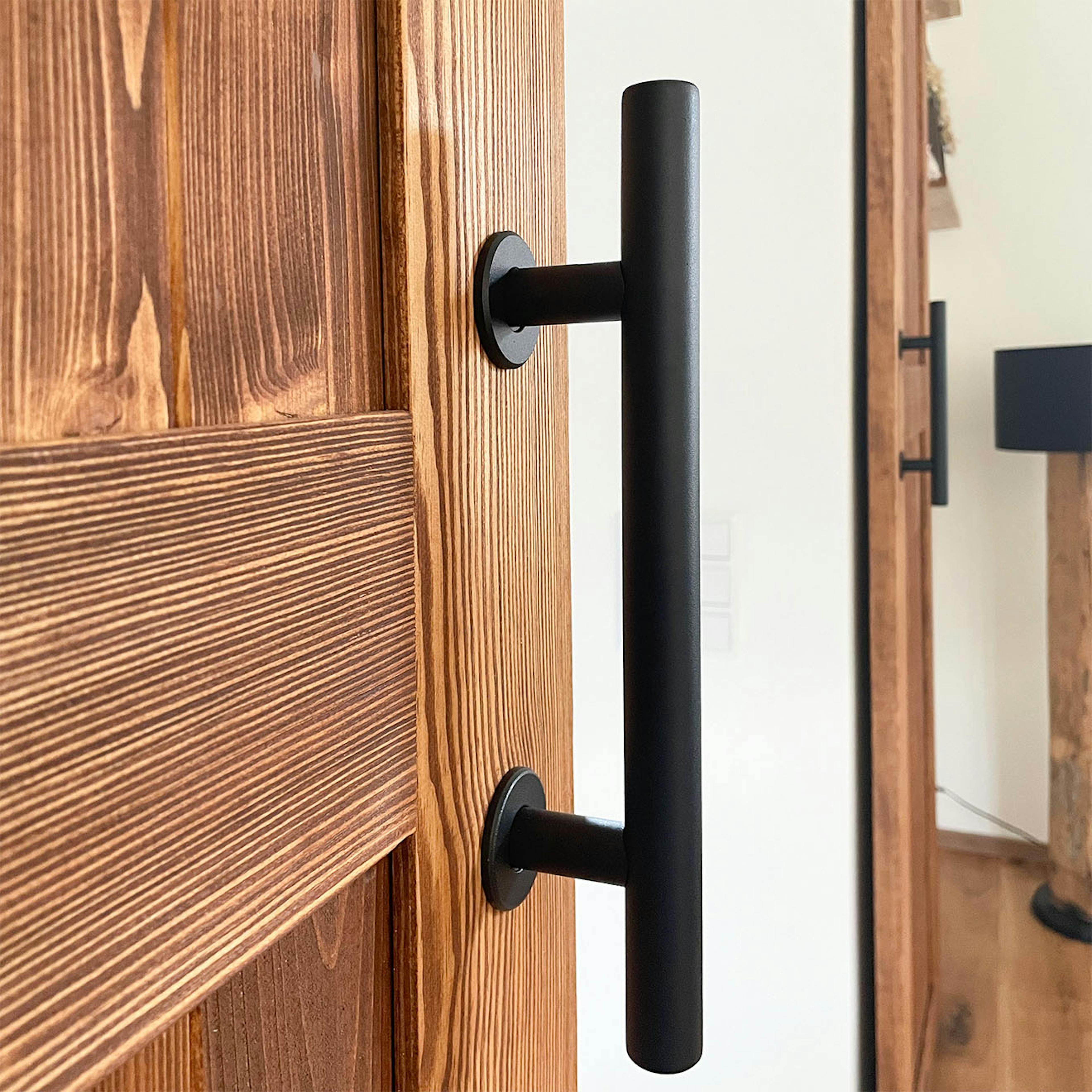 Détail de la poignée en métal noir sur une porte coulissante en bois rustique.