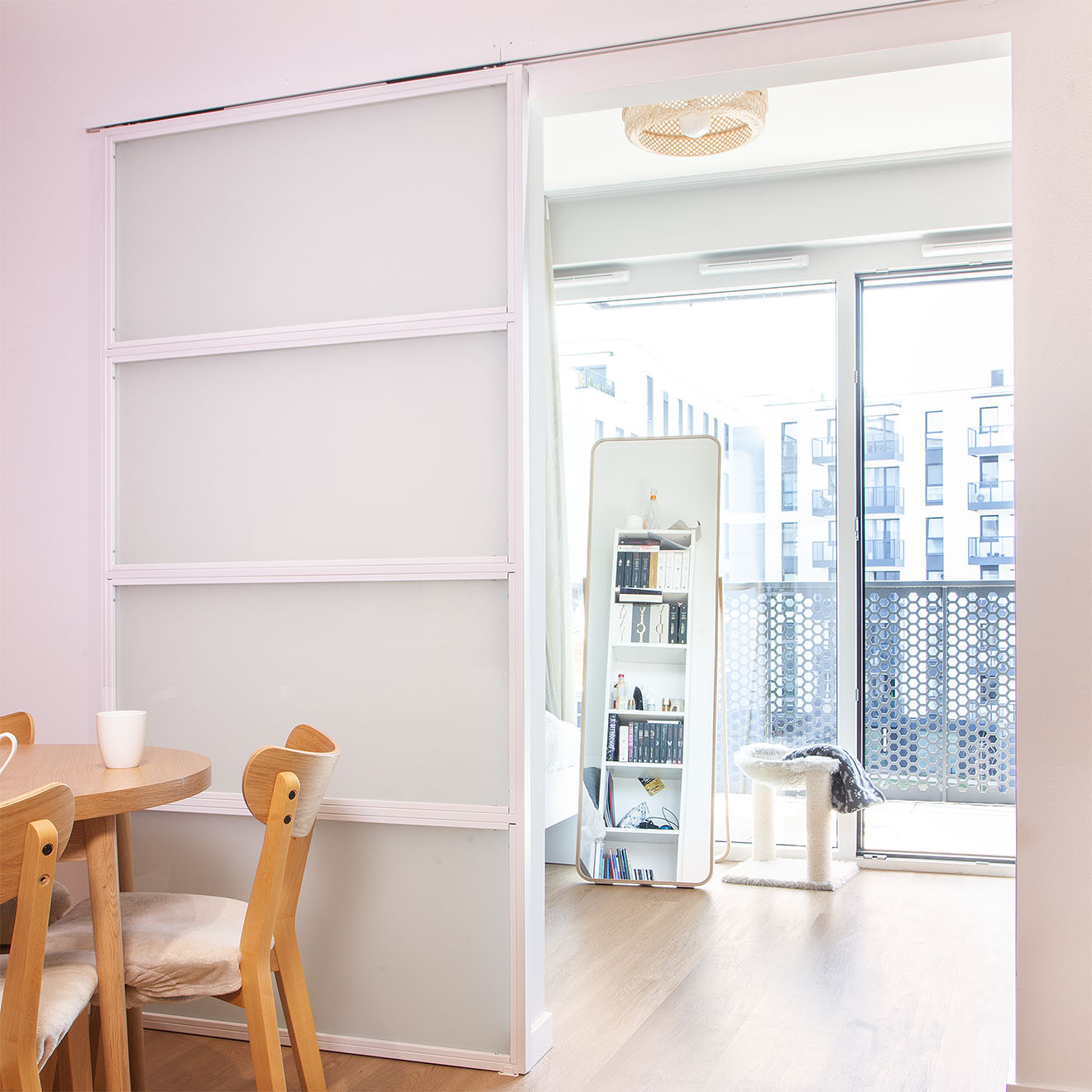 Offene, weiße Schiebetüren mit Milchglas, die einen Teil eines hellen Zimmers mit einem großen, stehenden Spiegel und einem Kratzbaum für die Katze zeigen.