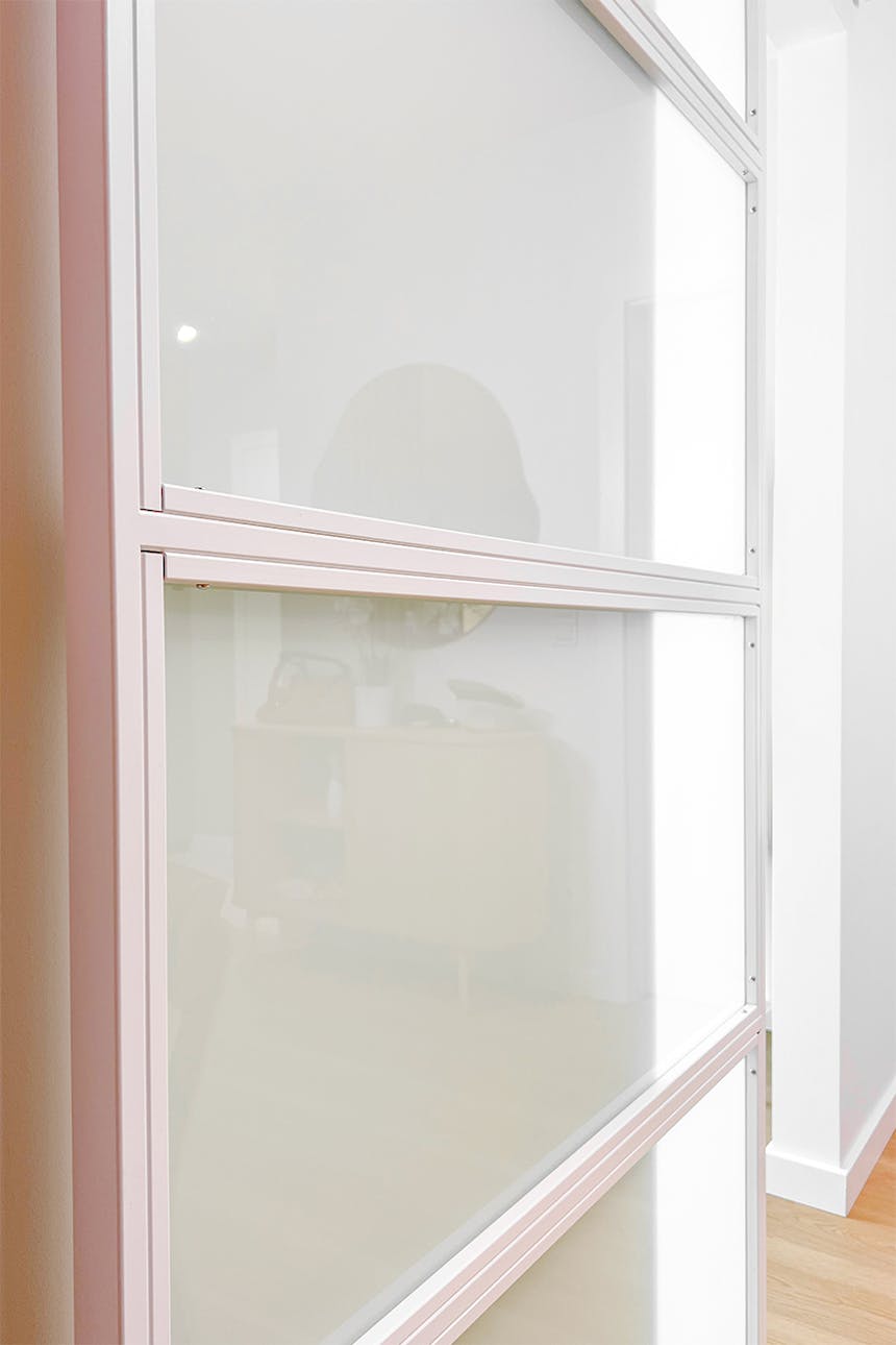 Nahaufnahme weißer Schiebetüren mit vier Milchglas-Paneelen, die ihre Konstruktion zeigen.