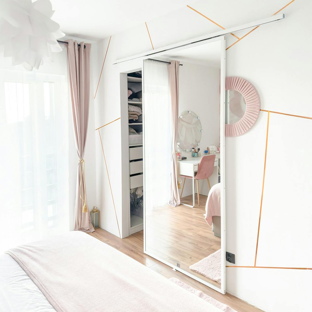 Schlafzimmer in Rosa und Grau; Ein großer Spiegel an der Schiebetür vergrößert optisch den Raum; Schminktisch und helle Vorhänge.