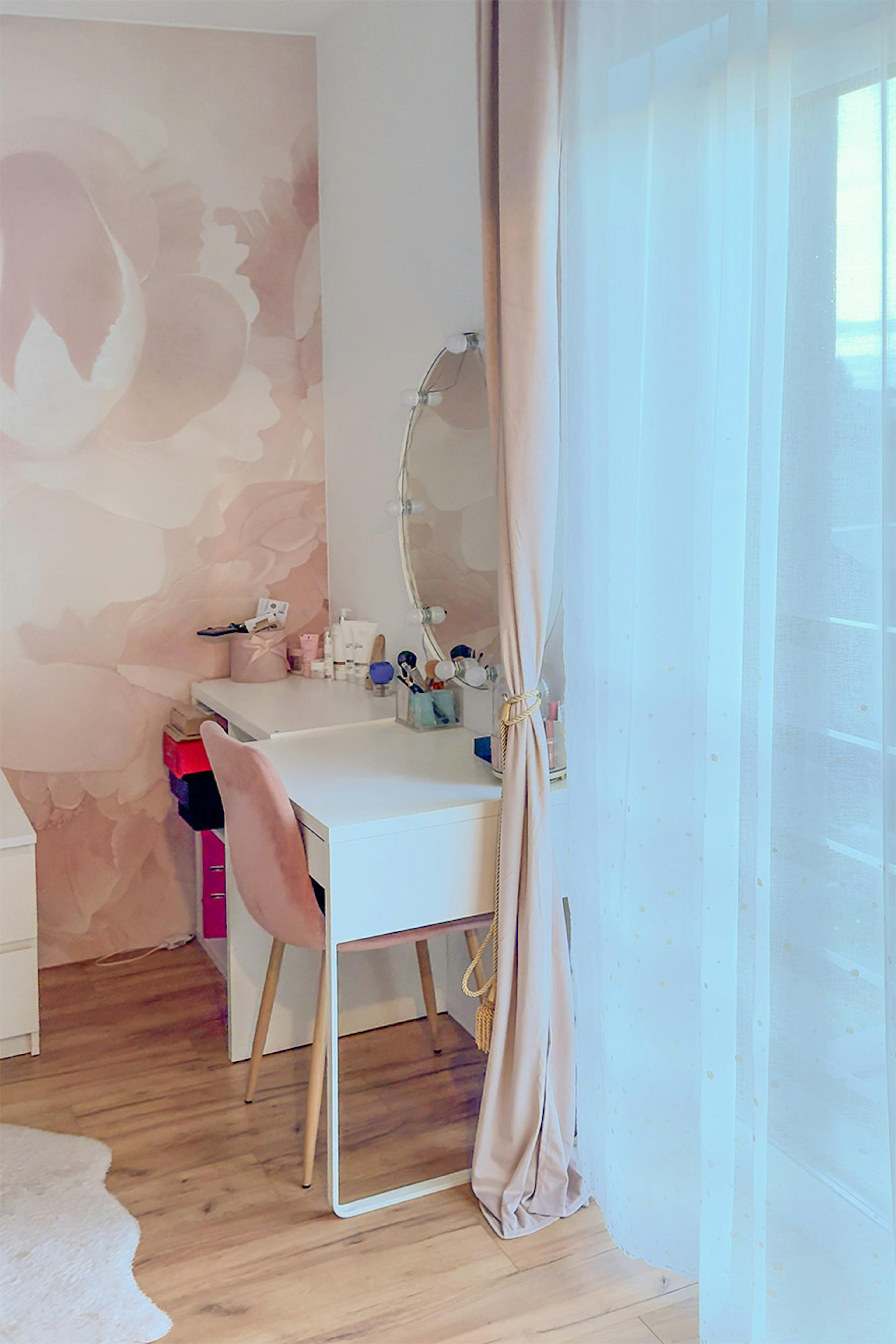 Bureau/coiffeuse blanc et chaise en velours rose ; miroir rond éclairé dans le style hollywoodien.