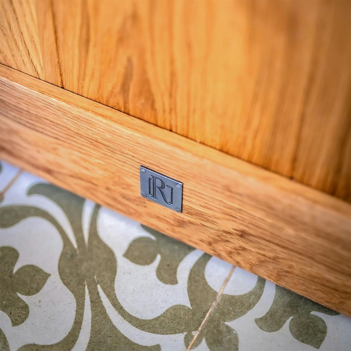 Detailansicht des unteren Teils einer Eichenschiebetür, die die Holzmaserung vor dem Hintergrund gemusterter Bodenfliesen zeigt.