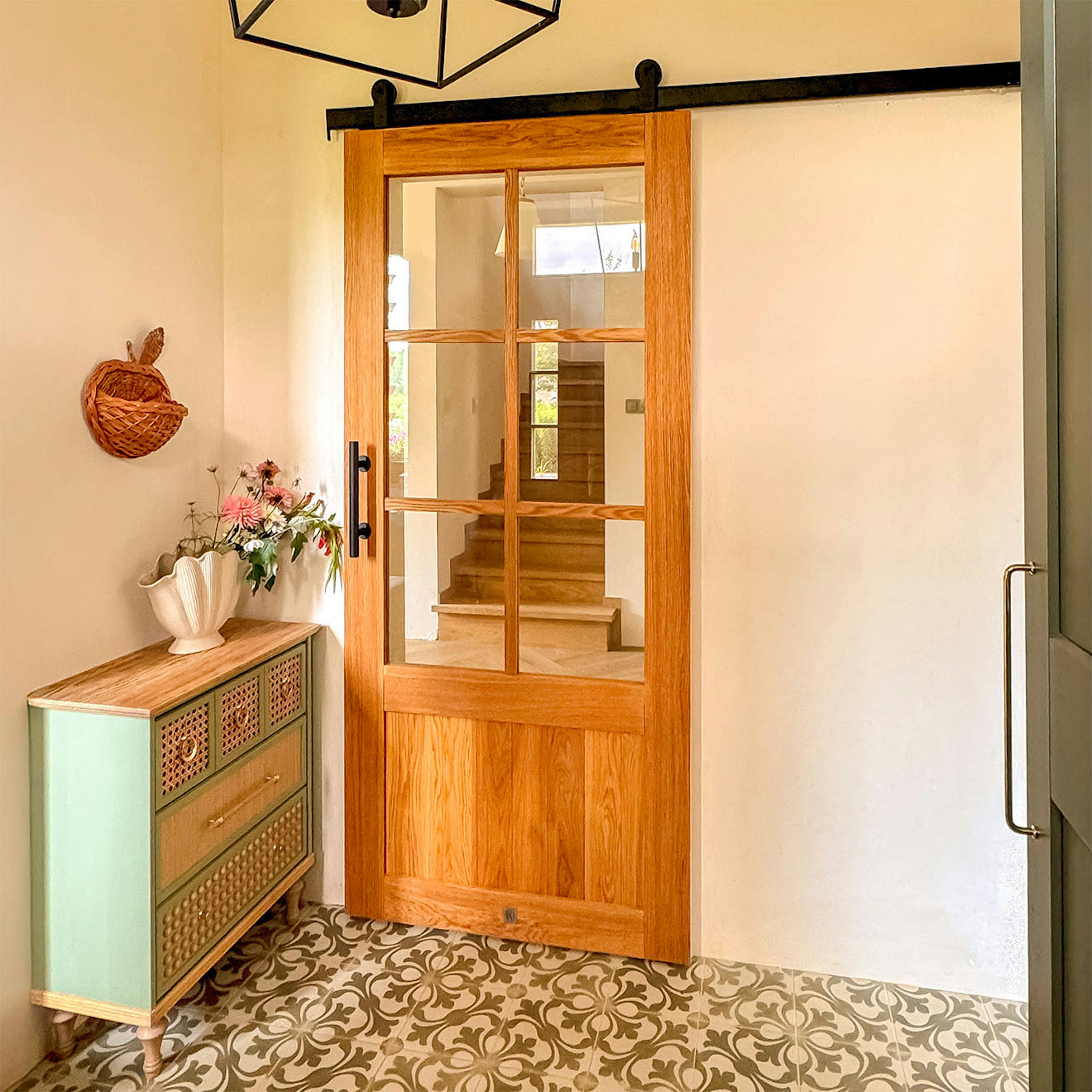 Portes coulissantes vitrées en chêne dans un vestibule aménagé avec une commode vert sauge et des carreaux de ciment à motifs.