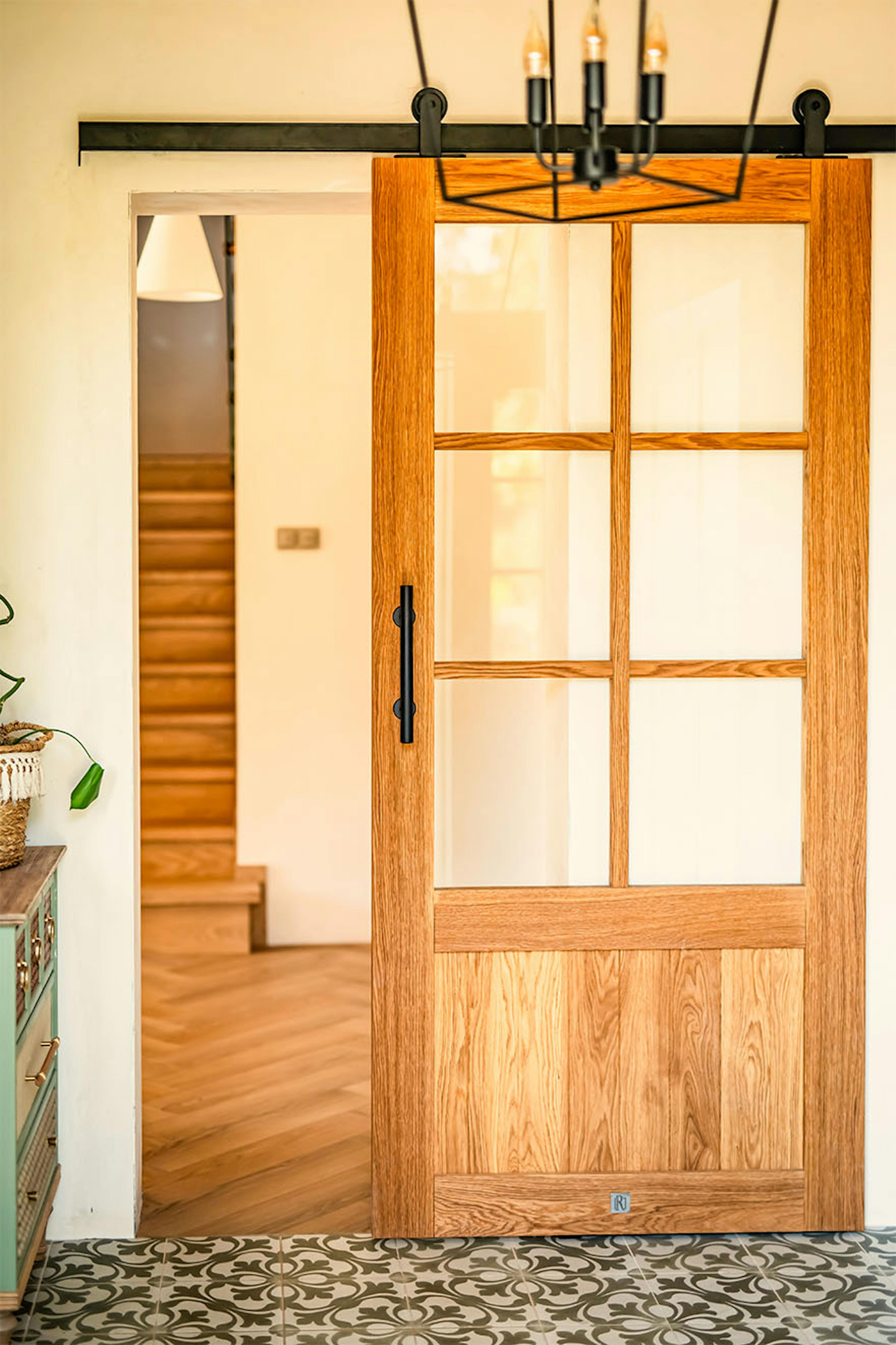 Porte coulissante en chêne de style "barn door" avec vitrage et petits bois, séparant le vestibule du couloir dans un esprit modern farmhouse.