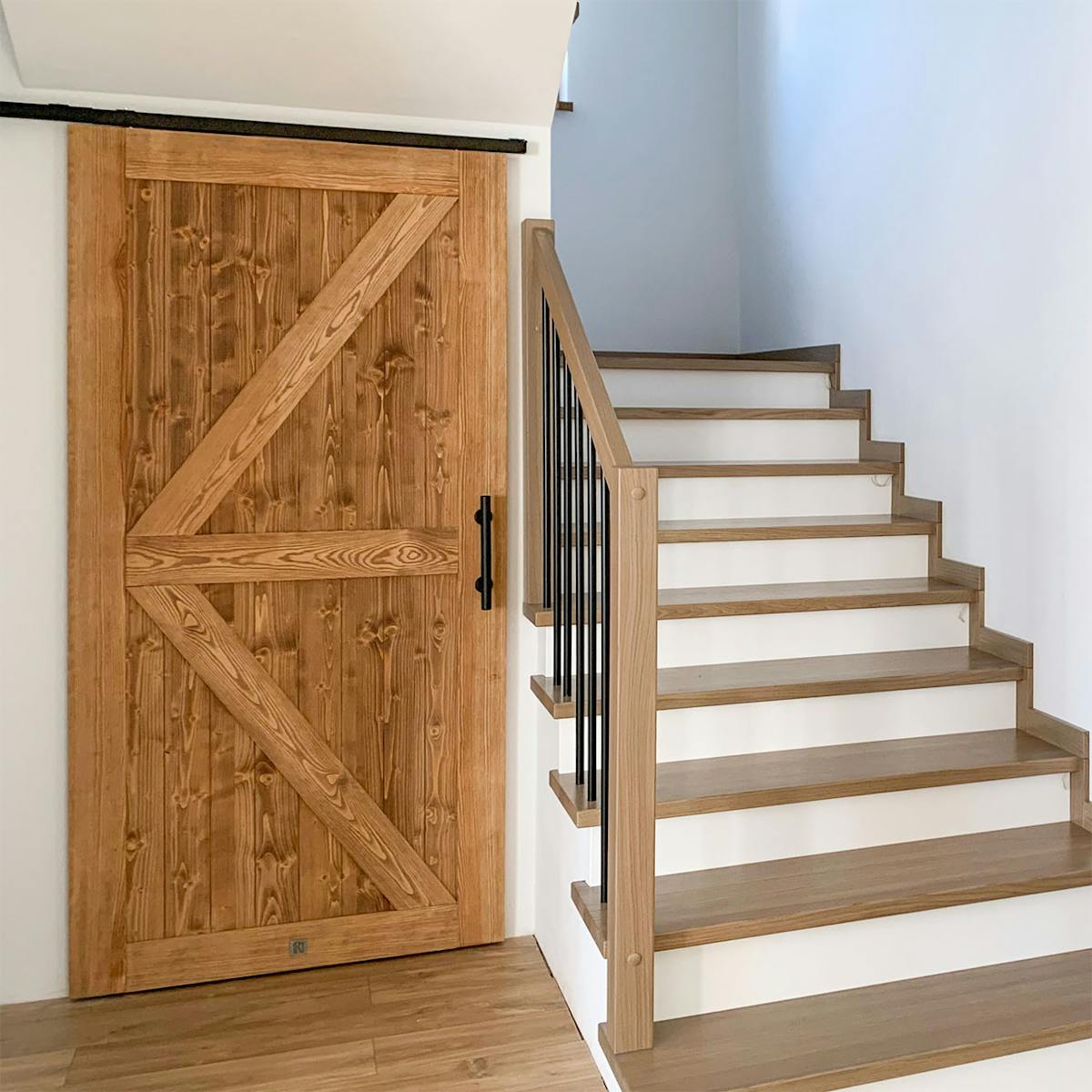 Holz-Schiebetüren im Barn-Door-Stil, montiert unter einer Dachschräge im Treppenbereich mit dem System TOP WALL.