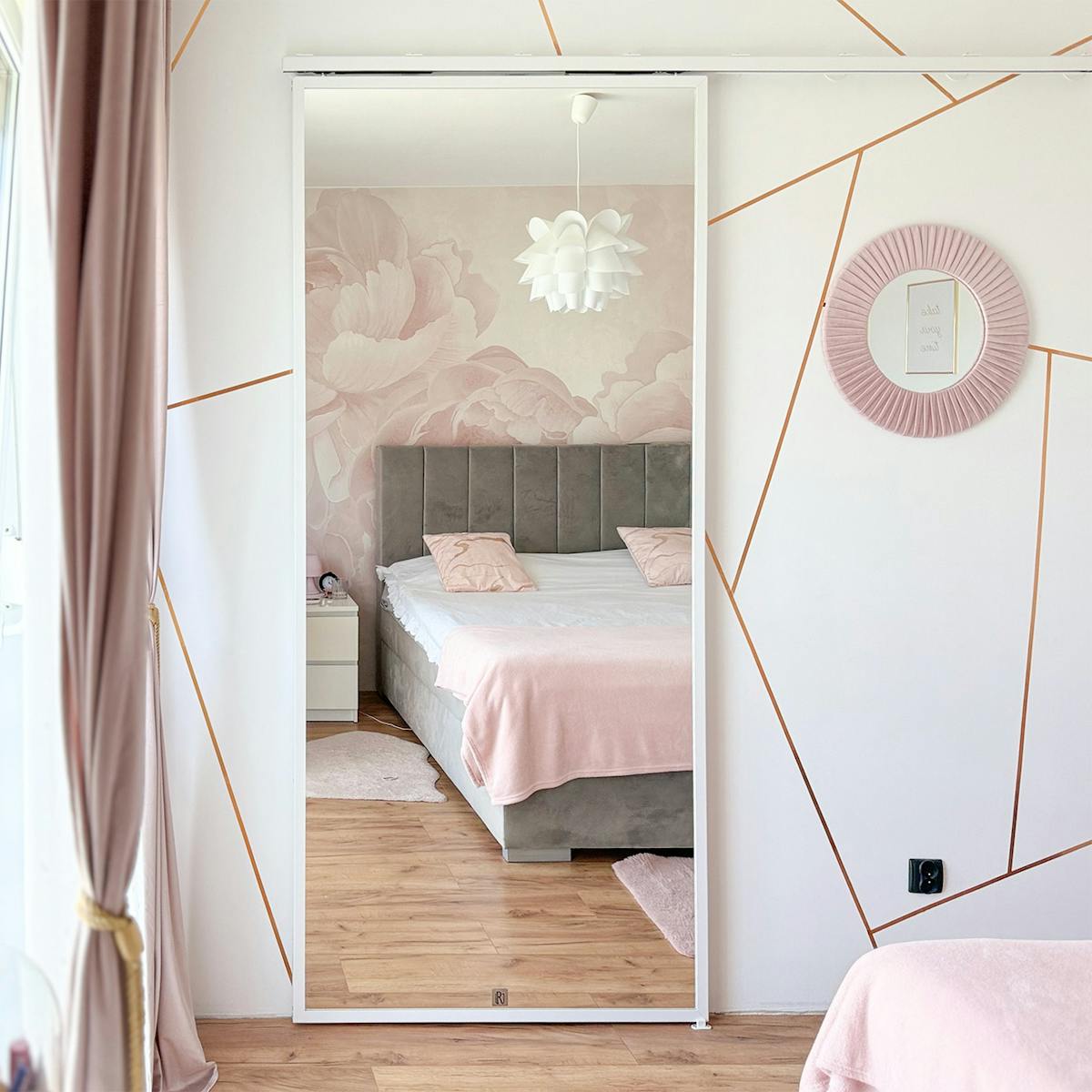 Weißes Schiebetürsystem TOP WALL mit Spiegel im Schlafzimmer – die diskrete Führungsschiene harmoniert perfekt mit der weißen Wand und dem geometrischen Dekor.