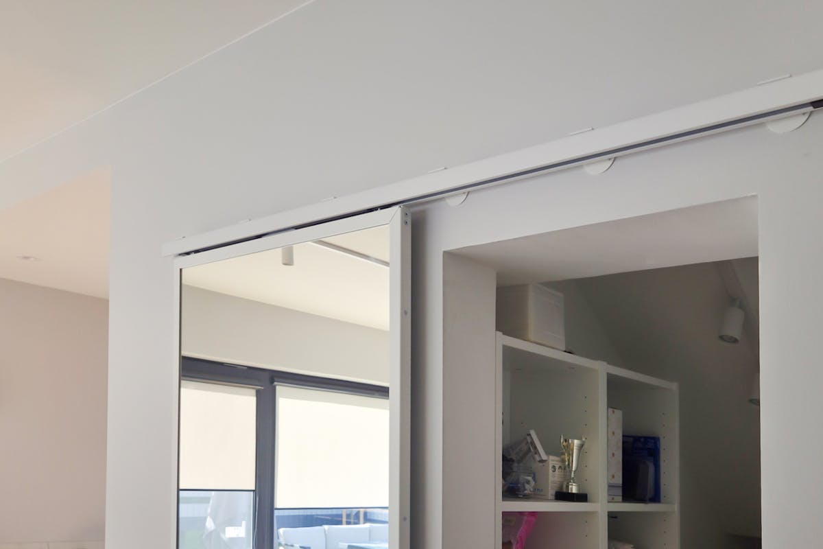 Schiebetürsystem TOP WALL mit Spiegel, montiert über der Türöffnung an der Führungsschiene.