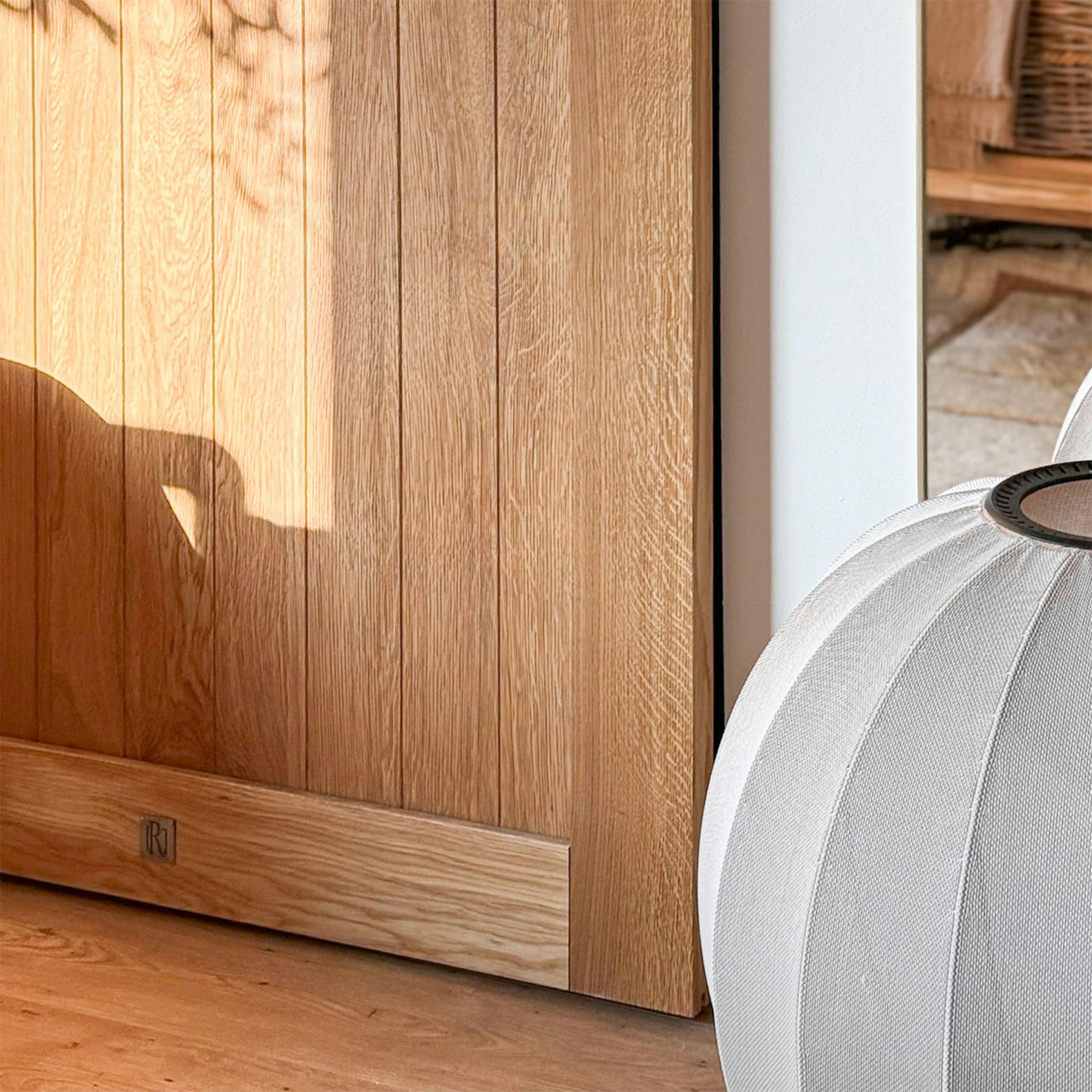 A close-up of the natural wood grain of an oak sliding door. The distinct oak grain and the play of light on the surface of the door leaf are clearly visible.