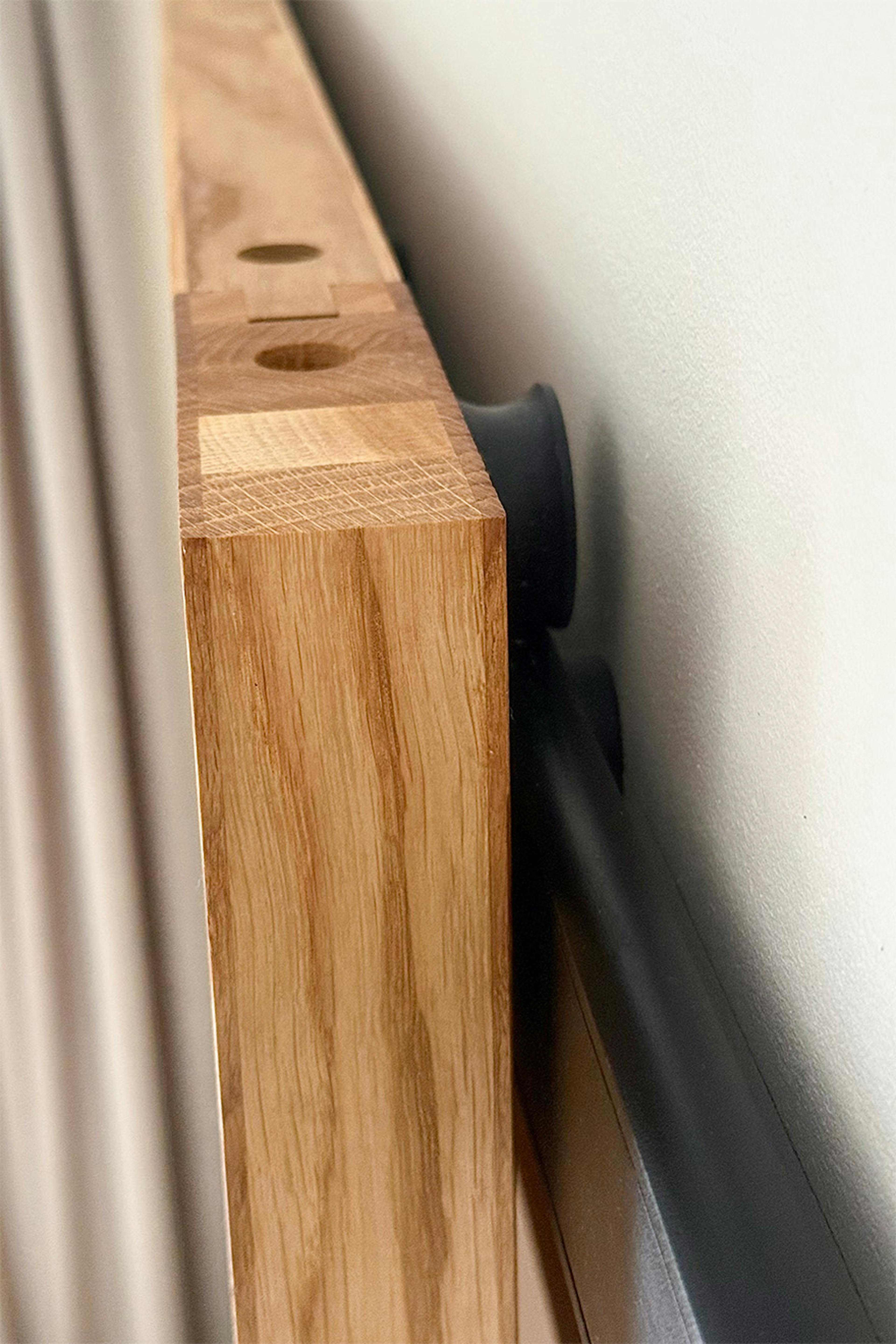 Gros plan sur un détail de fabrication des portes coulissantes en chêne et sur le système coulissant noir au design minimaliste.