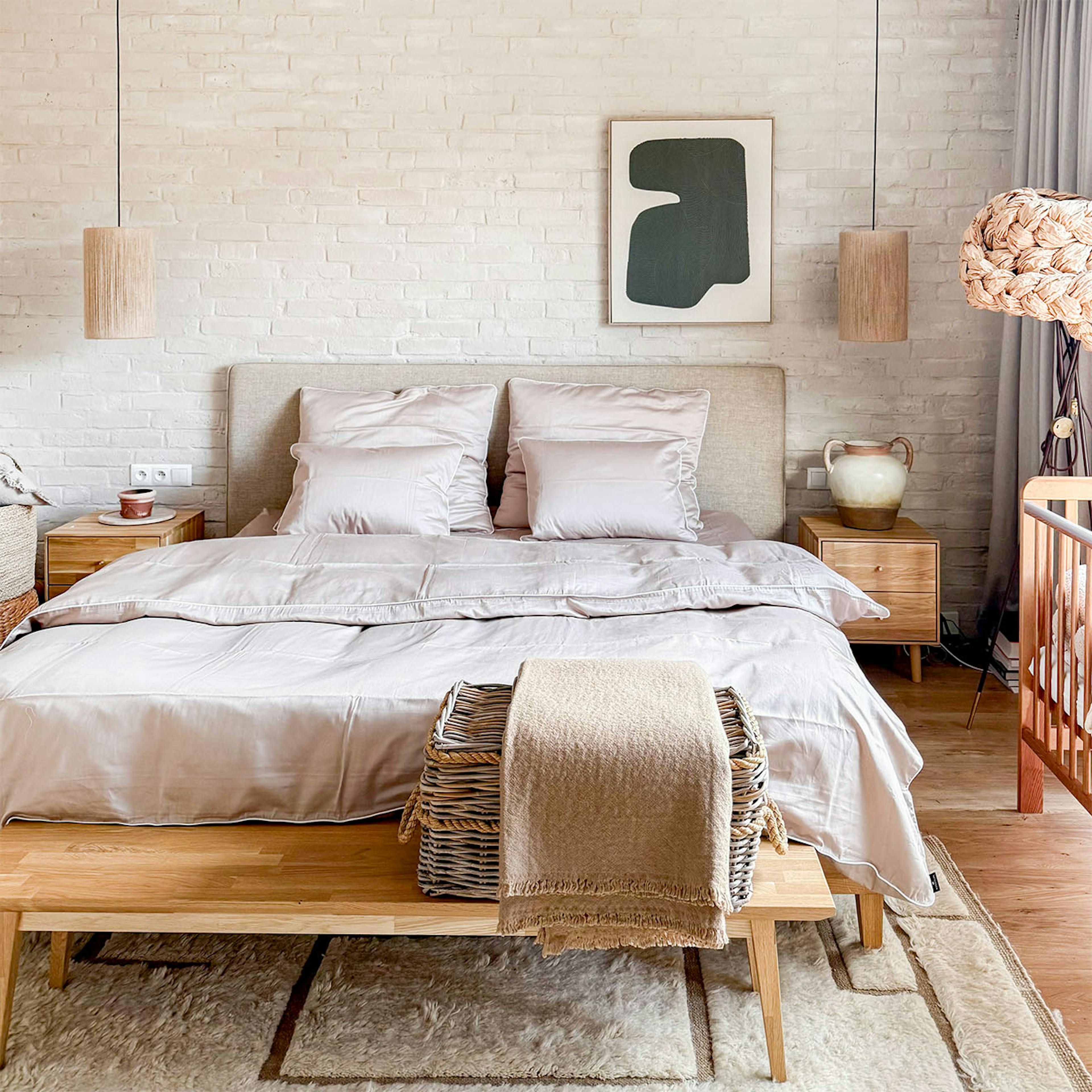 Une chambre à coucher beige de style minimaliste, avec un lit à cadre en chêne, un mur en briques blanches et des lampes en lin. Un intérieur harmonieux propice à la détente.