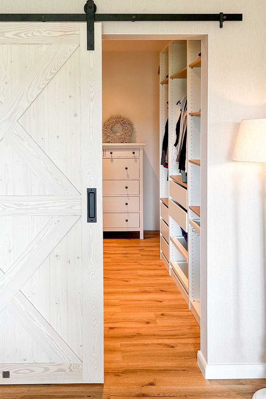weiße, rustikale Schiebetür zum Ankleidezimmer neben dem Schlafzimmer